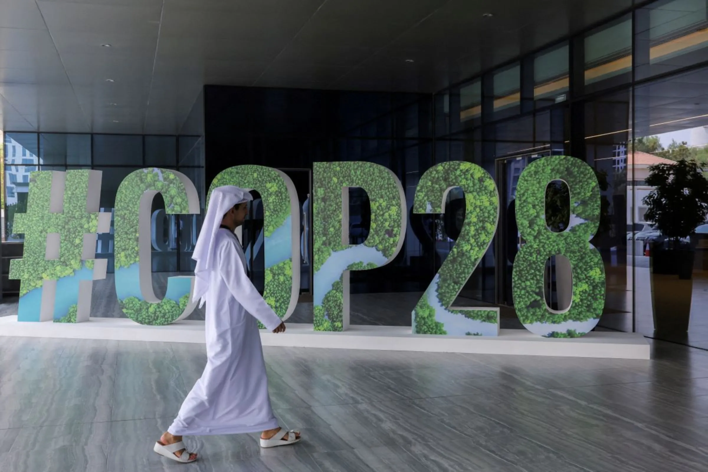 A person walks past a '#COP28' sign during The Changemaker Majlis, a one-day CEO-level thought leadership workshop focused on climate action, in Abu Dhabi, United Arab Emirates, October 1, 2023