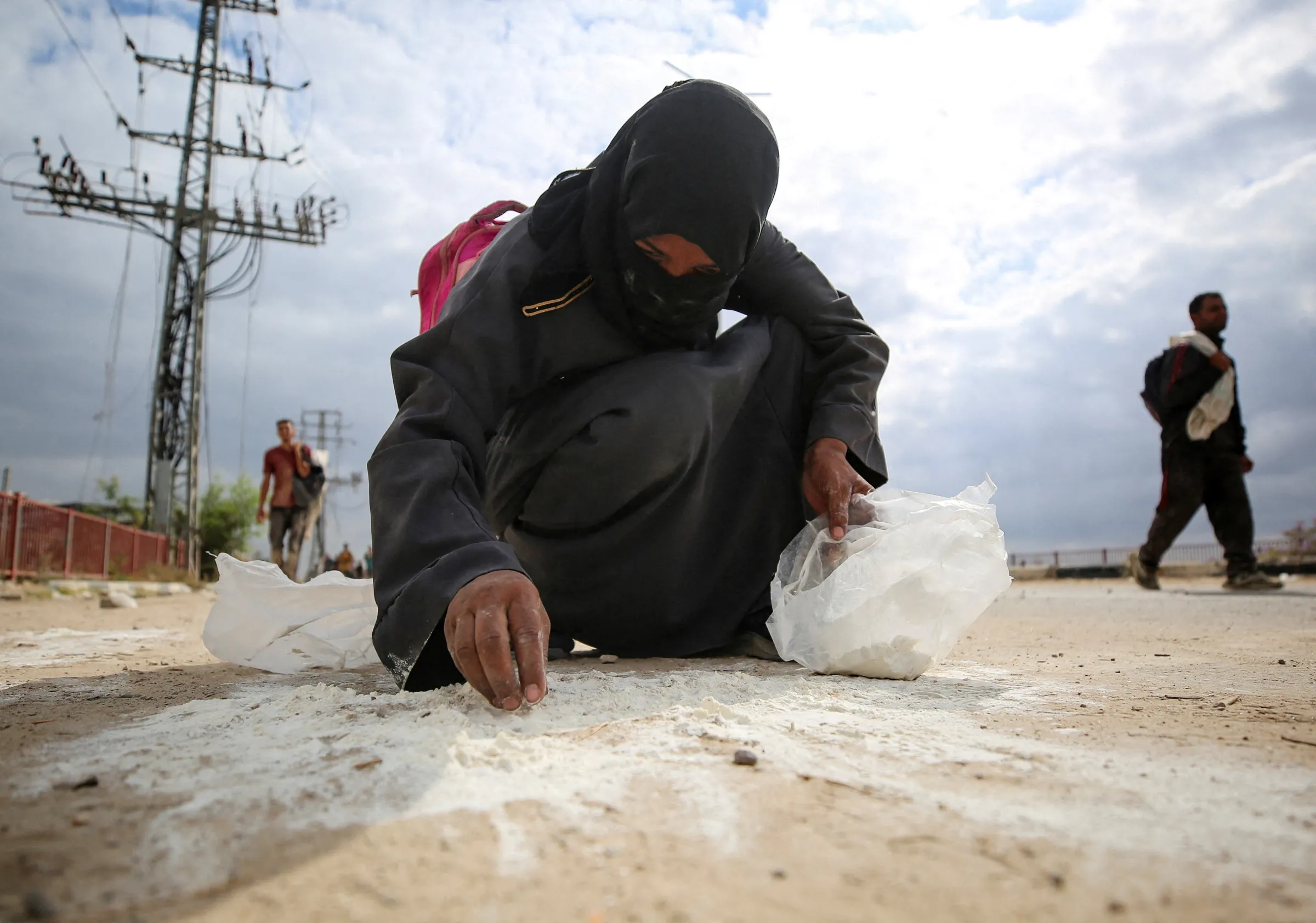 A woman collects flour from the ground as Palestinians receive aid supplies from the Gaza Humanitarian Foundation (GHF) in Gaza, August 1, 2025. REUTERS/Stringer