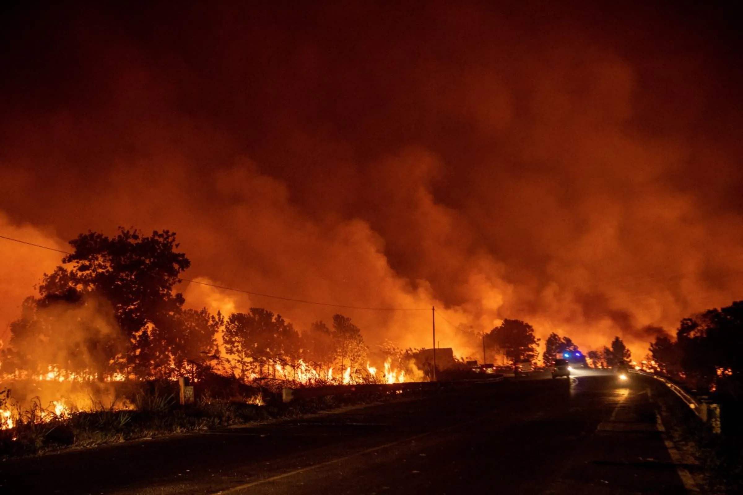 Motorists drive on a road as wildfire burns in North Indralaya, Ogan Ilir regency, South Sumatra province, Indonesia, September 14, 2023