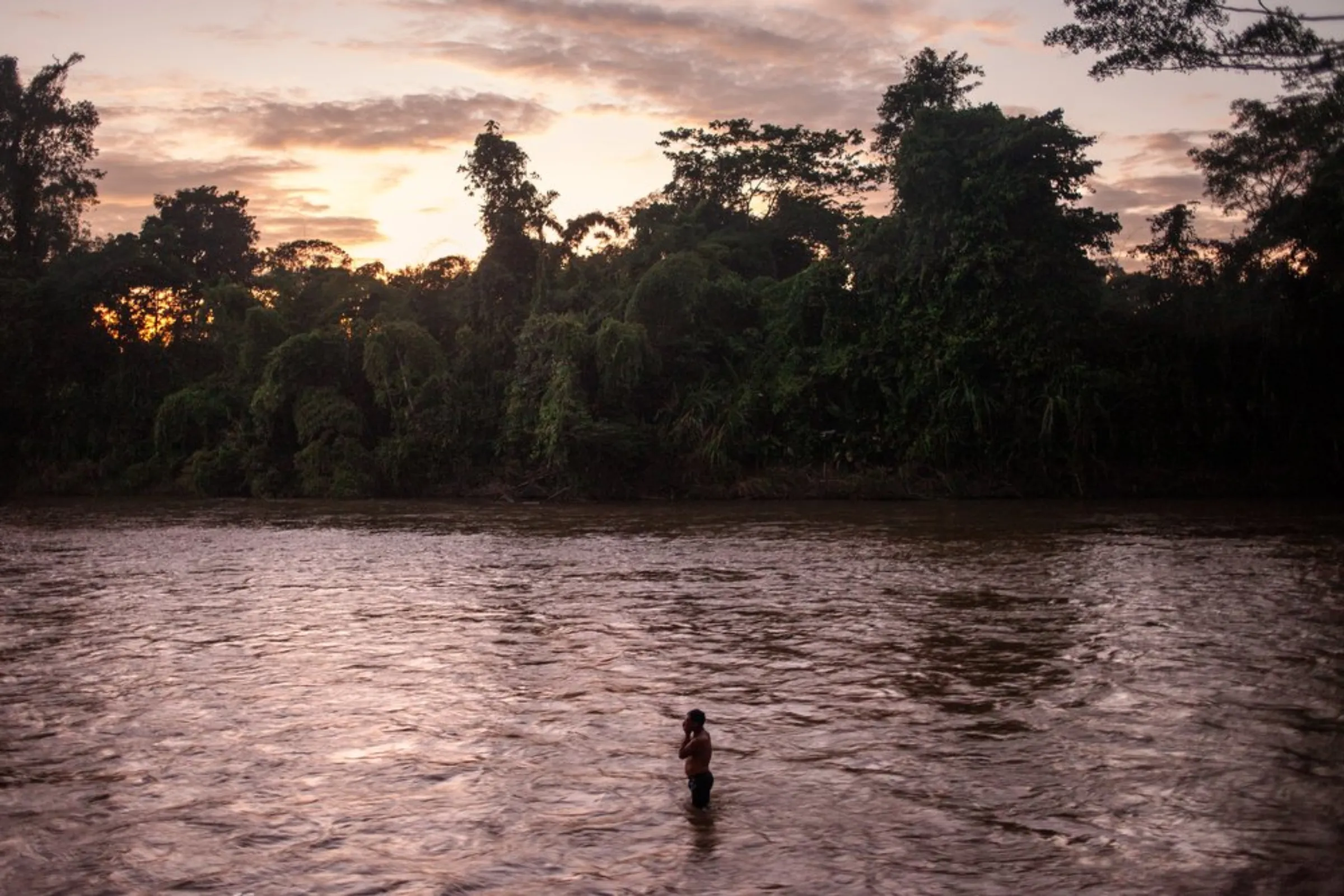 A man from the Waorani of Pastaza indigenous group bathes in the Curaray River at sunset in the Amazon province of Pastaza, Ecuador, on April 25, 2022