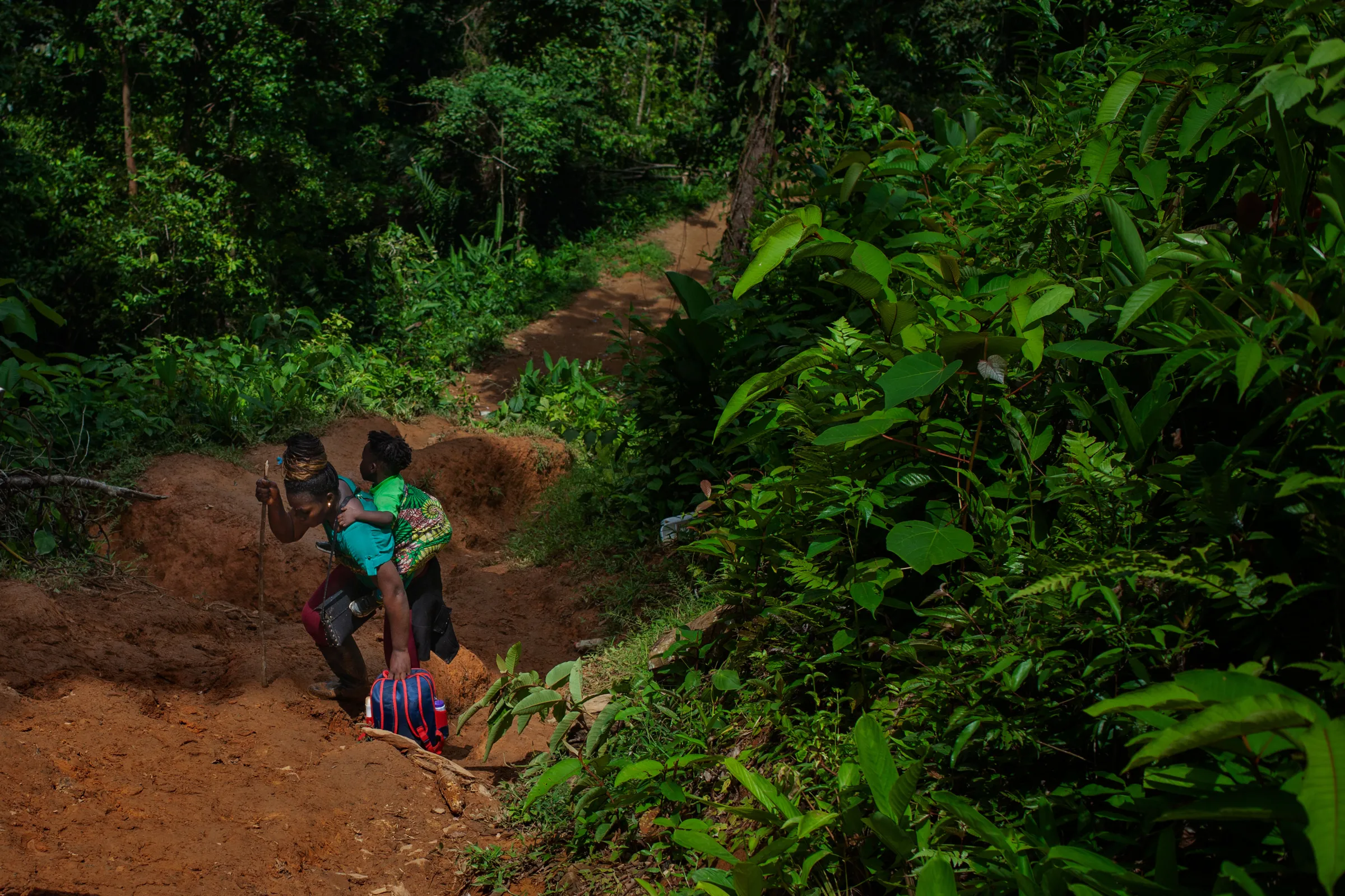A migrant from Sierra Leone carries her child as she climbs up a Colombian jungle path through the Darién Gap, Colombia July 27, 2022. Thomson Reuters Foundation/Fabio Cuttica