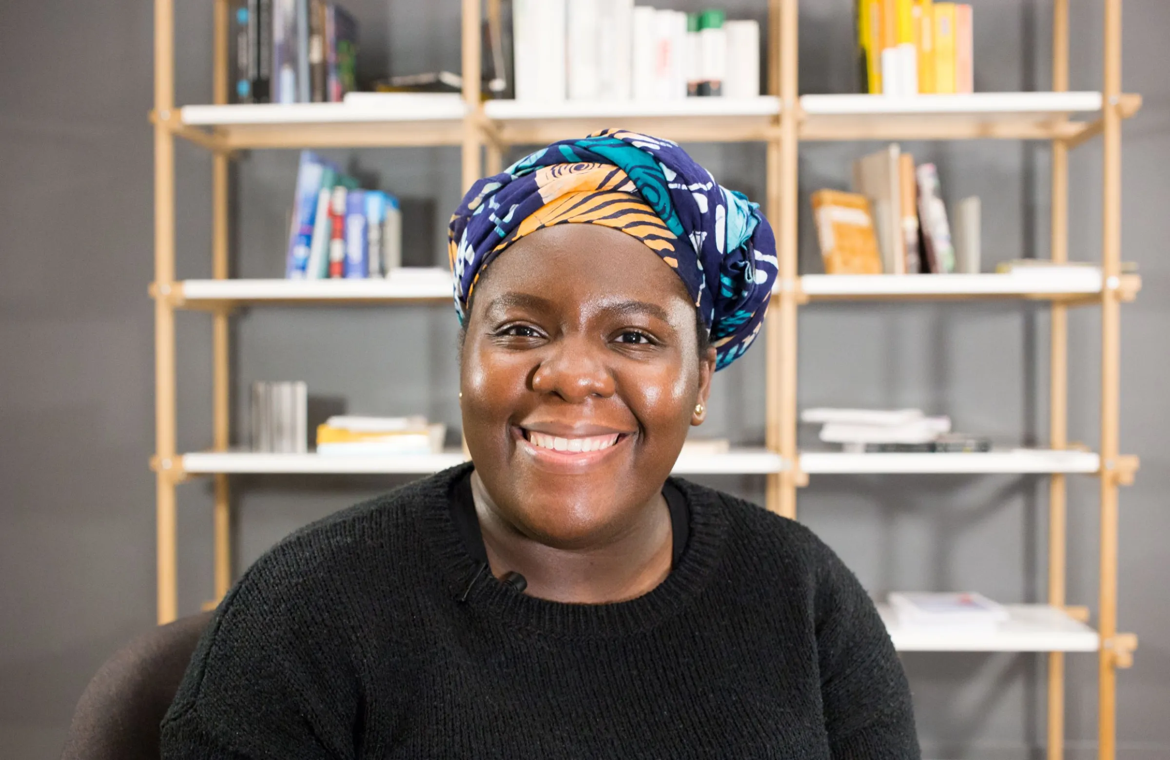 A woman poses for a photo in front of a book shelf