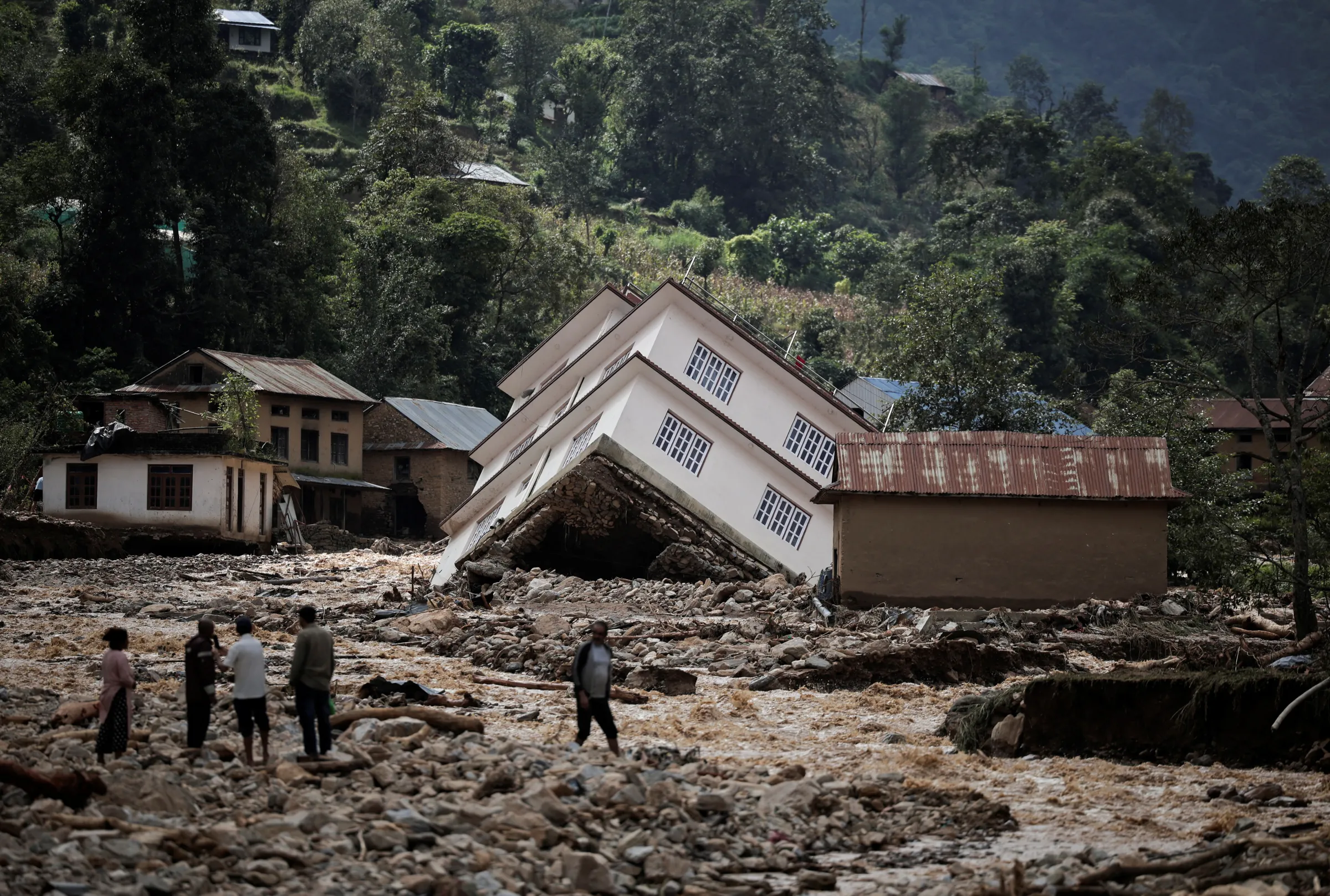People walk along the damaged houses swept by flood following heavy rainfall along the bank of Roshi River at Panauti in Kavre, Nepal September 30, 2024. REUTERS/Navesh Chitrakar
