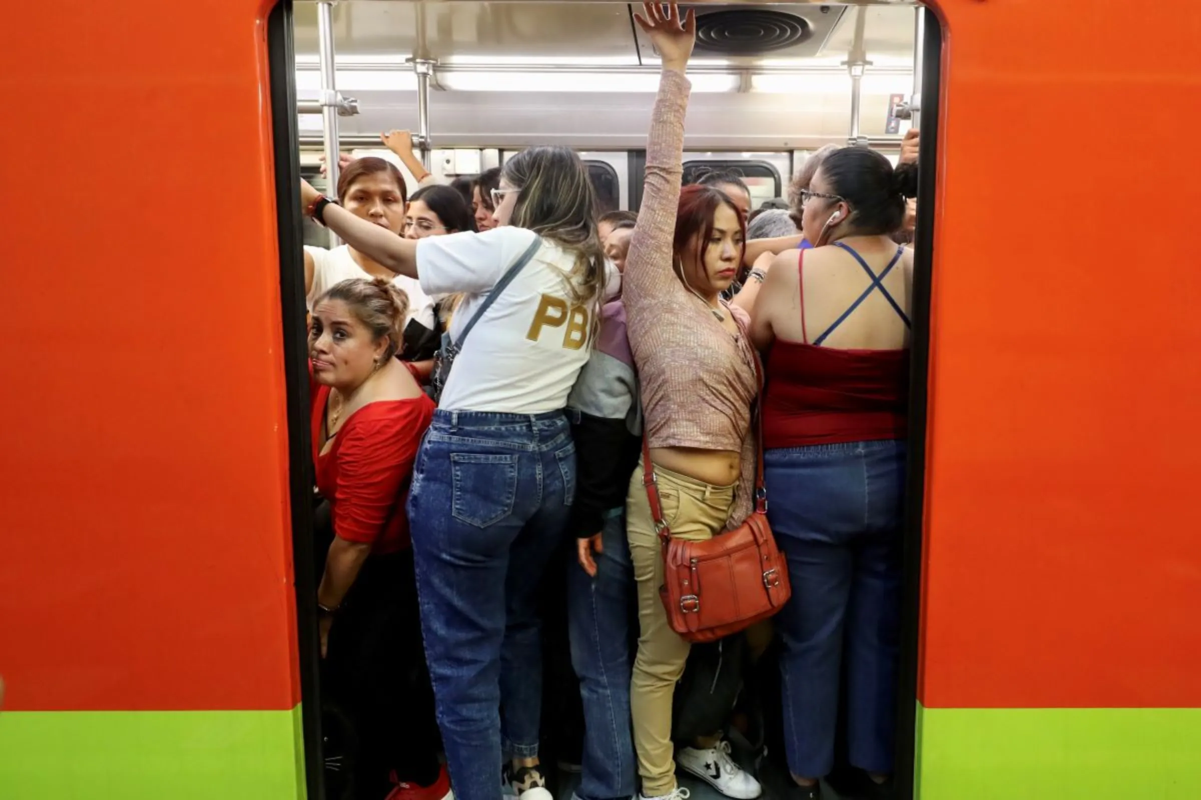 Women struggle to board a crowded subway car in Mexico City, April 28, 2023. Mexican women have benefitted from government action to ensure tax cuts are passed on. Thomson Reuters Foundation/Vicente Castillo
