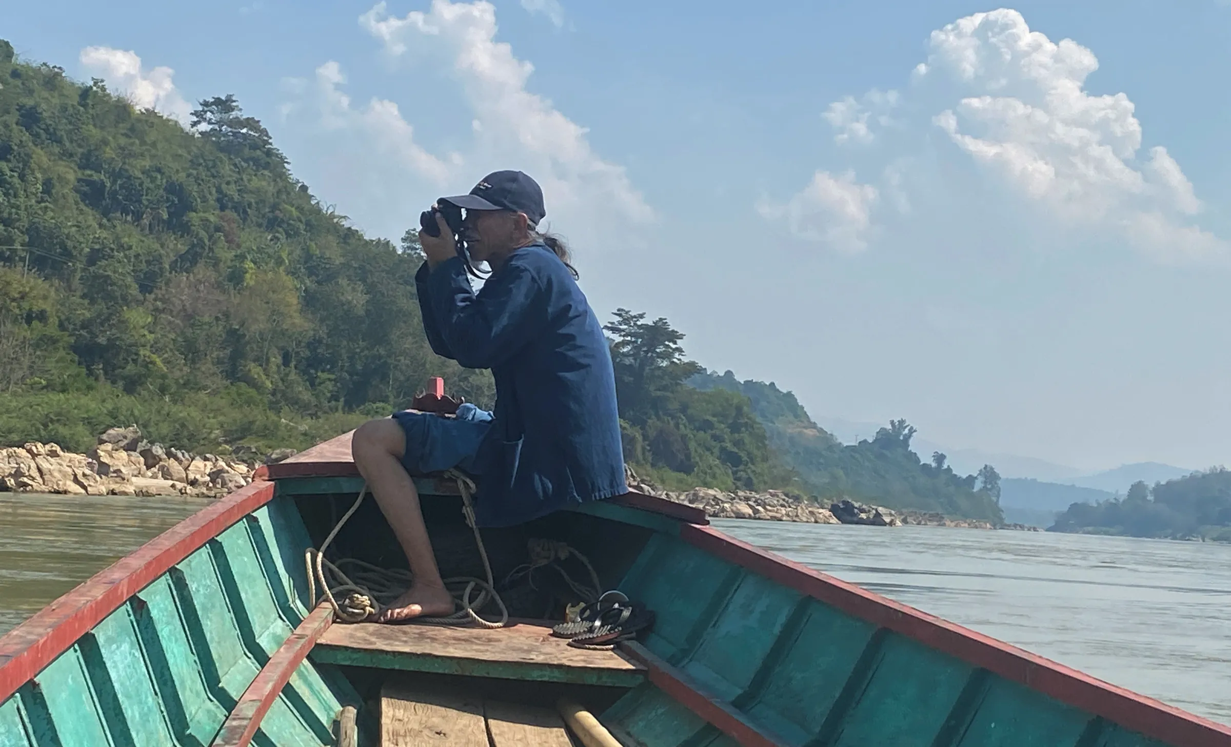 Conservationist Niwat Roykaew takes a picture on a boat on the Mekong River along the Thai-Laos border. February 6, 2023. Thomson Reuters Foundation/Rina Chandran