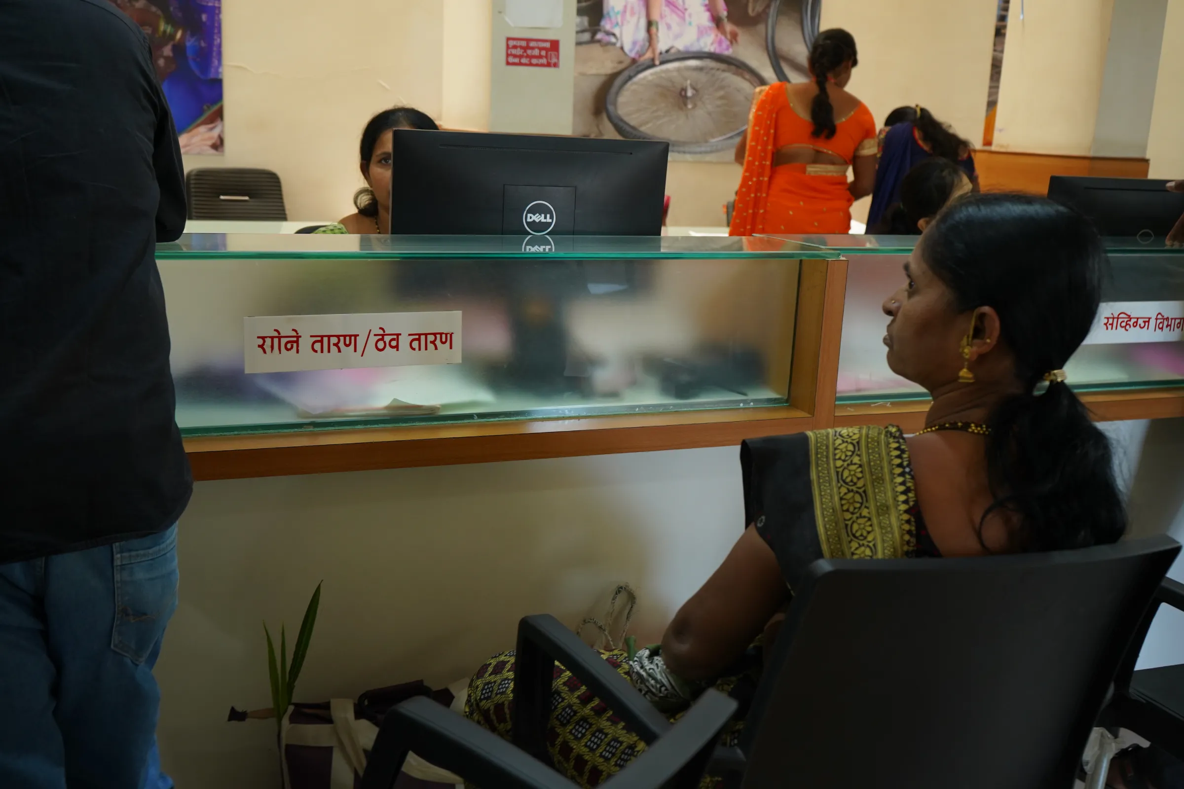 A woman sits on a bank counter that has a sticker with “gold mortgage” written on it in Marathi at Mann Deshi bank in Mhaswad village of Satara district, India, September 14, 2022