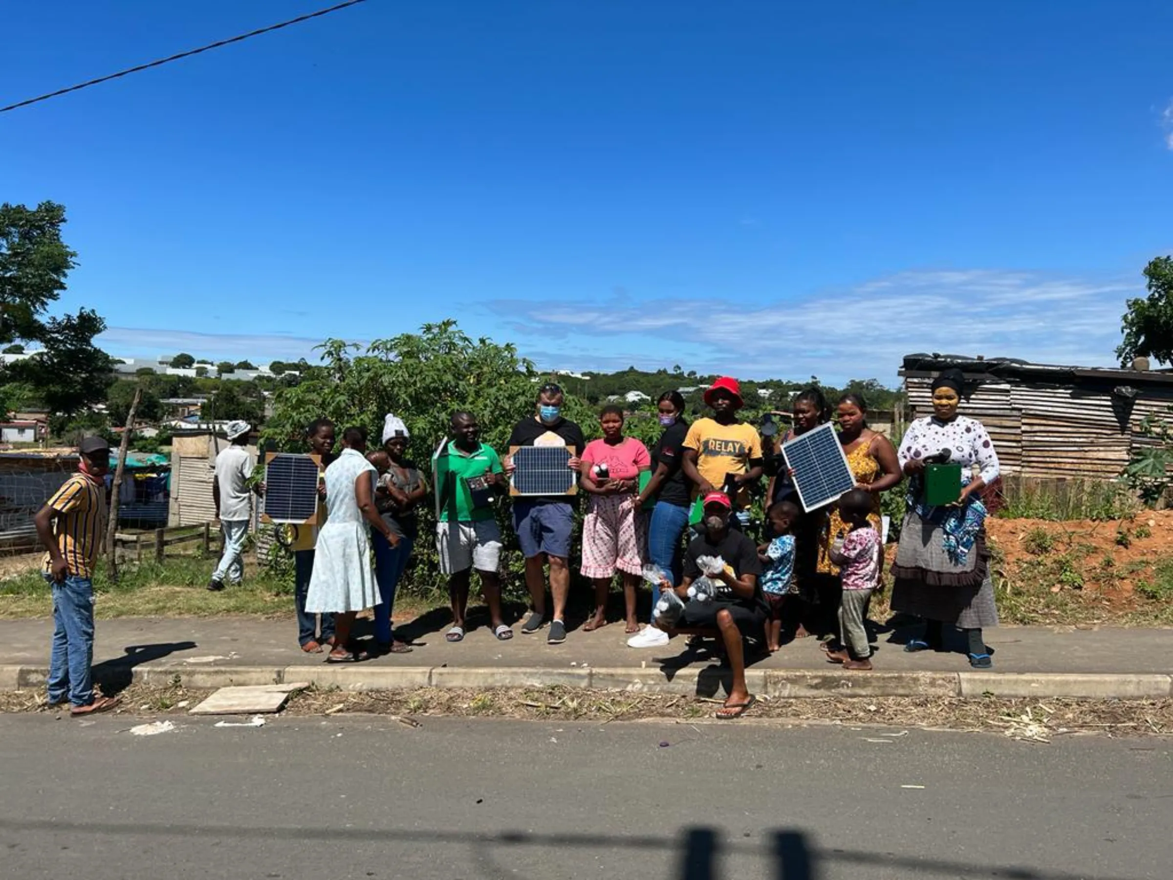 A dozen community members stand alongside the road holding their solar panels in KwaDukuza, KwaZulu-Natal, South Africa, January 2021. Balwin Foundation/Handout via Thomson Reuters Foundation