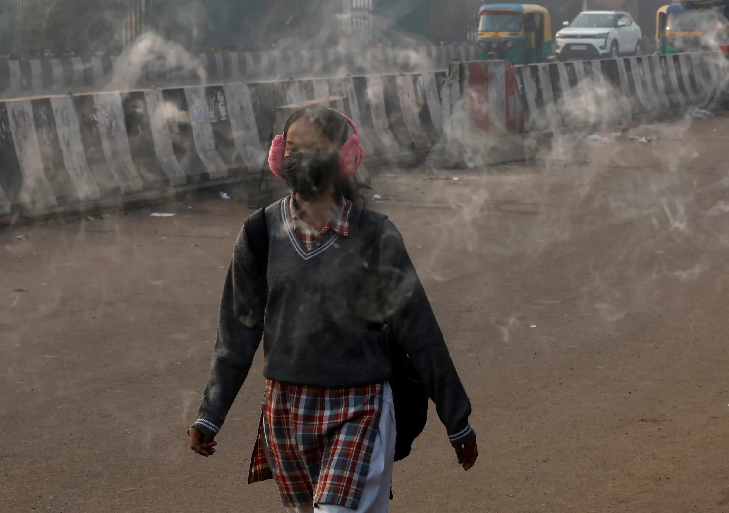 A girl wearing a mask to protect herself from air pollution walks through incense smoke, as the sky is enveloped in smog in New Delhi, India, December 17, 2024. REUTERS/Priyanshu Singh