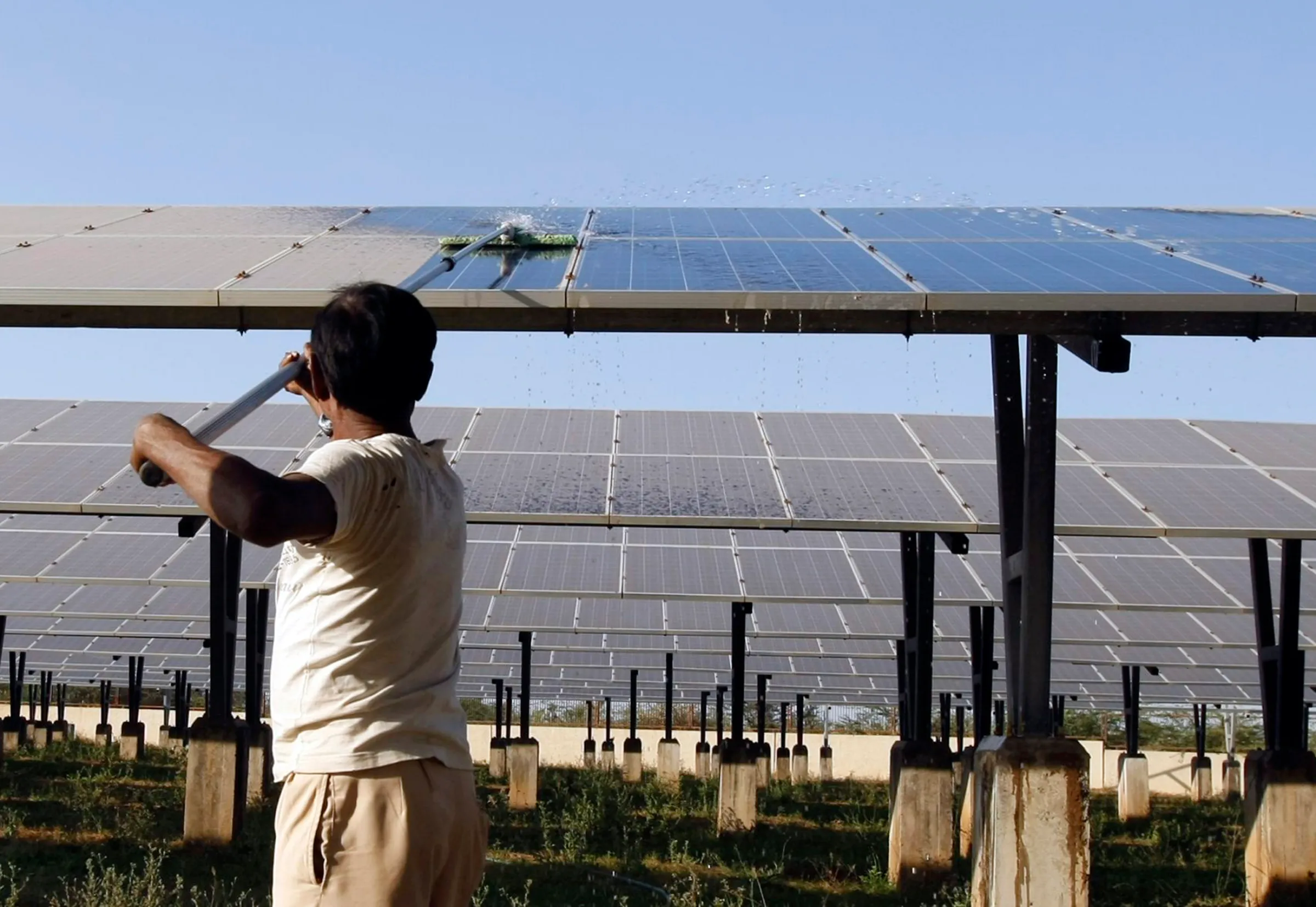 A worker cleans photovoltaic solar panels inside a solar power plant at Raisan village near Gandhinagar, in the western Indian state of Gujarat, February 11, 2014