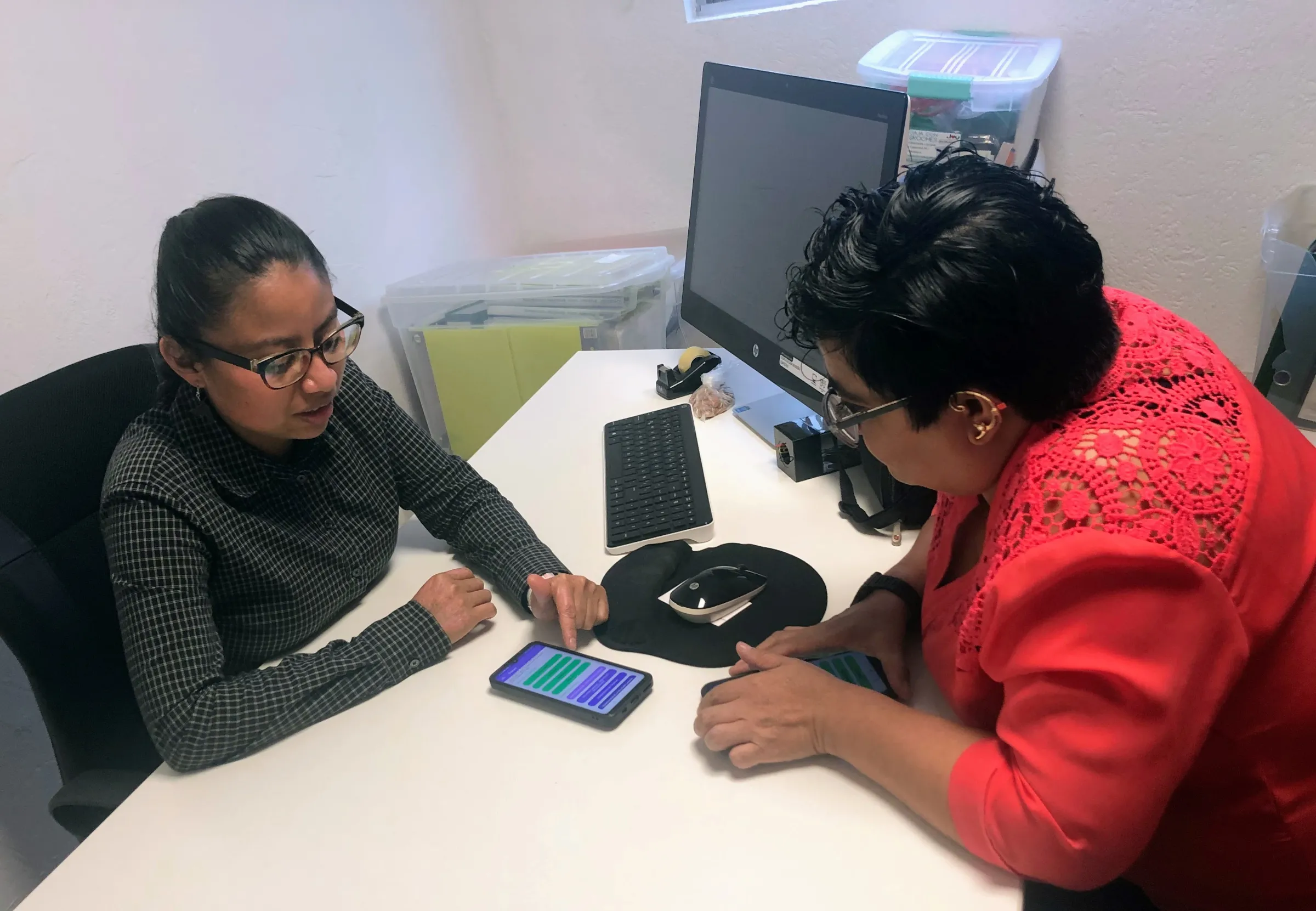Ana Sofia Pablo and Diana Enriquez, members of nonprofit CACEH, explore the app Dignas on their phones at their office in Mexico City, August 19, 2022