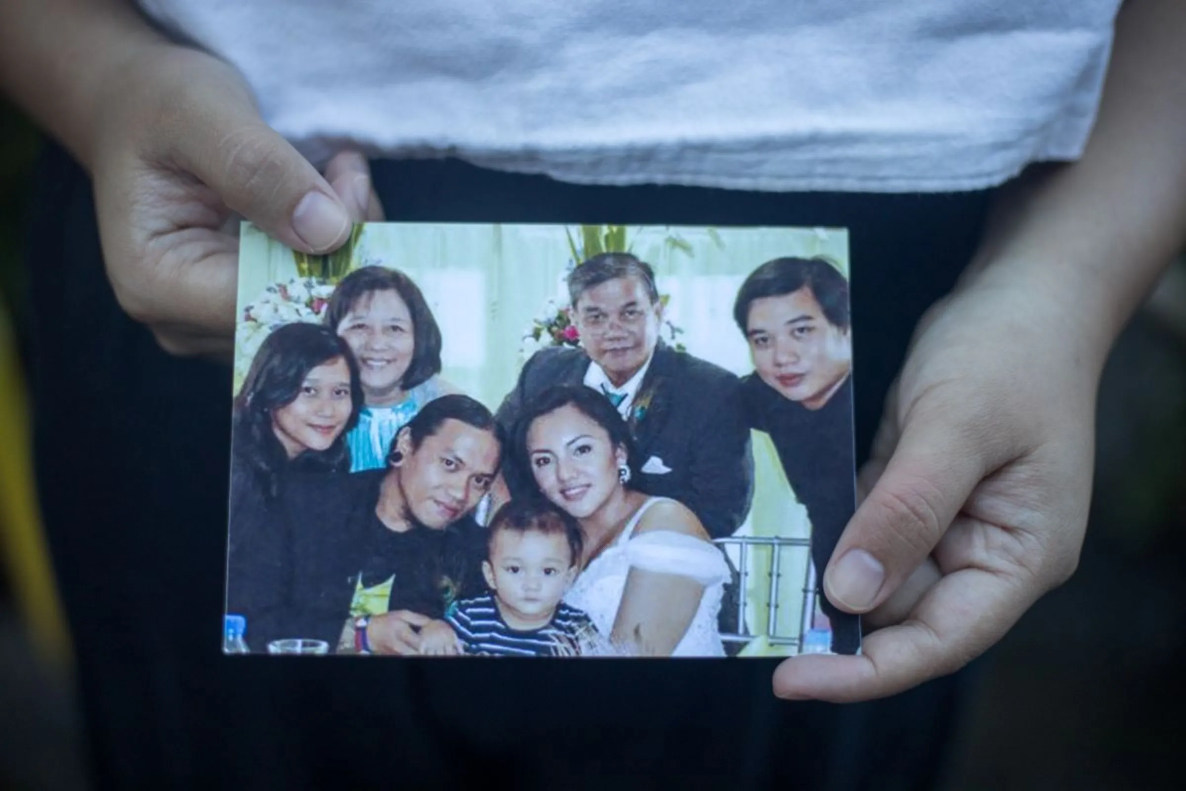 Joanna Sustento, a survivor of Super Typhoon Haiyan in 2013, shows photos of her loved ones. She lost her parents and sibling when a storm surge hit their home in Tacloban City, Philippines. October 7, 2023. Thomson Reuters Foundation/Kathleen Lei Limayo.