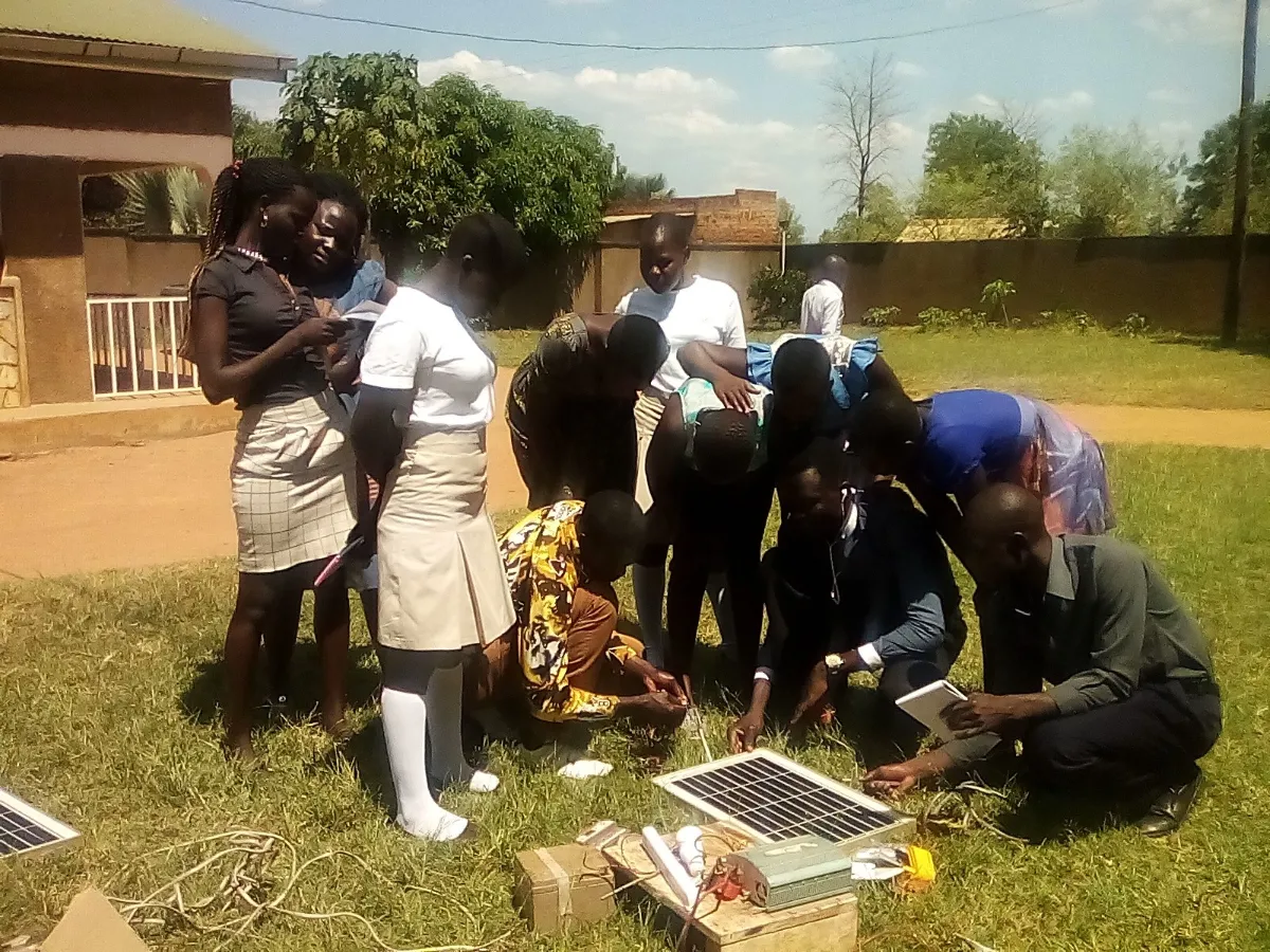 People gather around a solar panel during a training session run by BOSCO in Kitgum in Uganda. Thomson Reuters Foundation/Handout courtesy of BOSCO