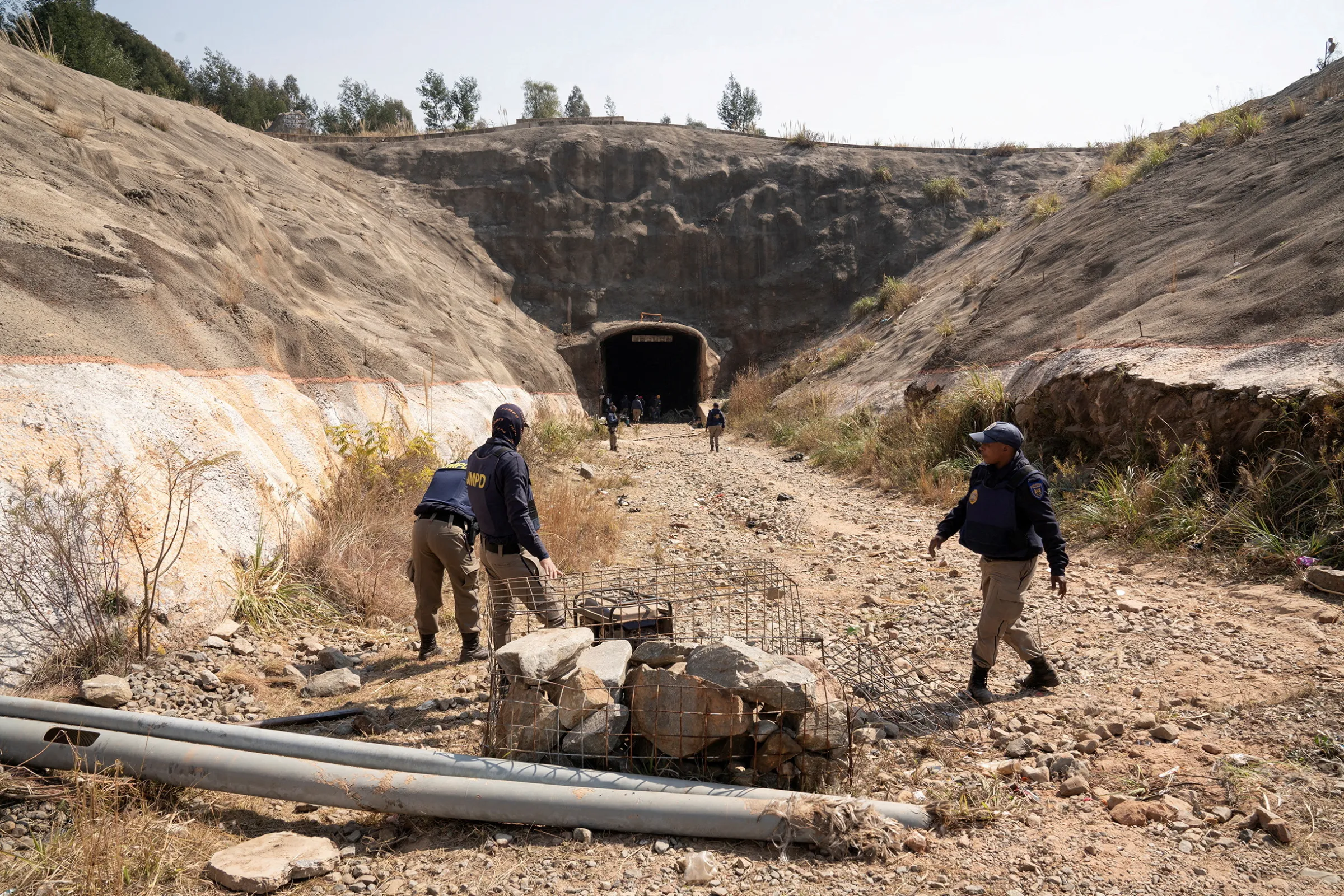 Johannesburg police officers walk at the entrance of an abandoned mine, after a gun battle between illegal miners and police in the west of Johannesburg, South Africa, August 5, 2023. REUTERS/Shiraaz Mohamed