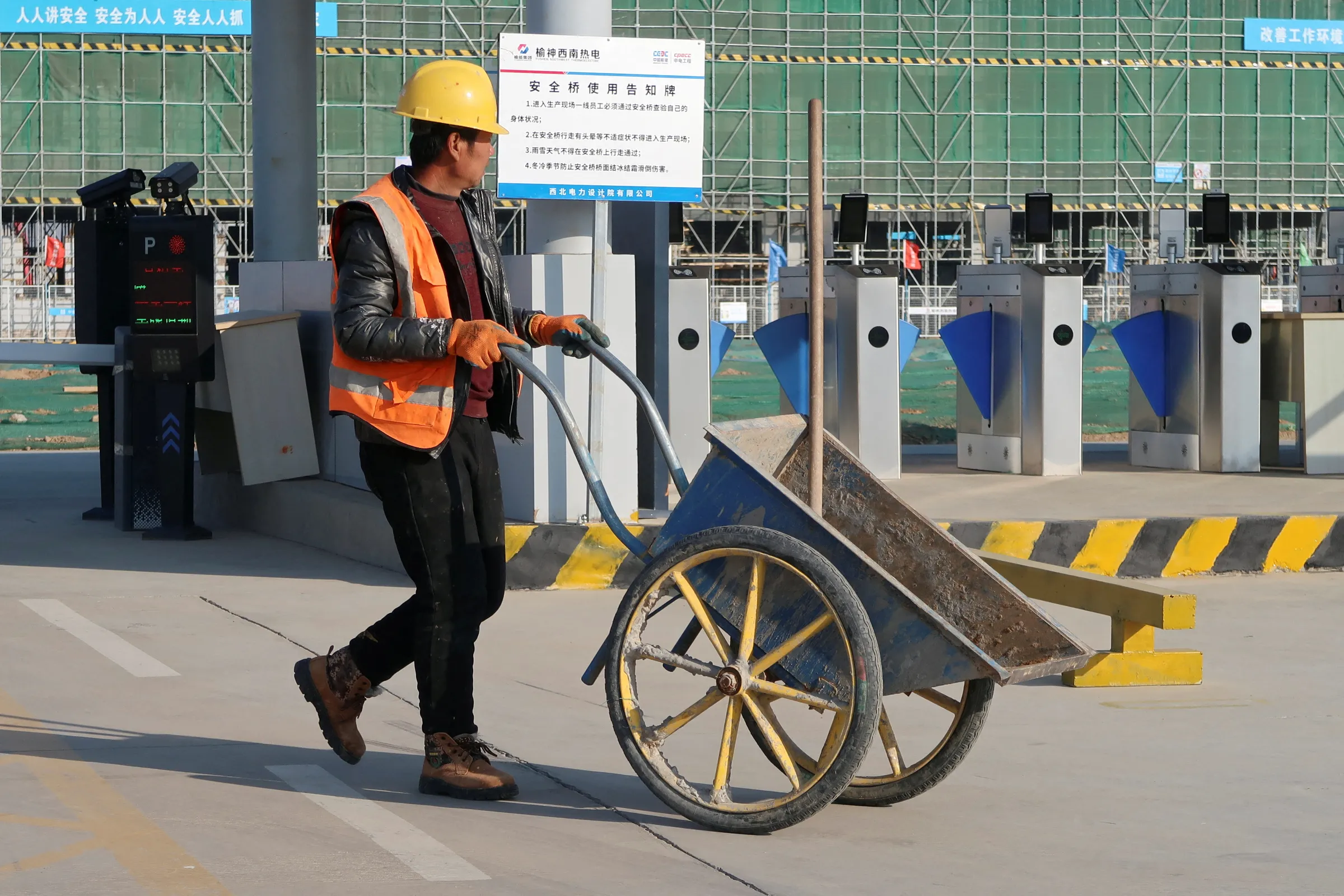 A construction worker pushes a wheelbarrow in front of the Yushen Yuheng power plant, a coal-fired power plant under construction, in Yulin, Shaanxi province, China November 21, 2023. REUTERS/Colleen Howe