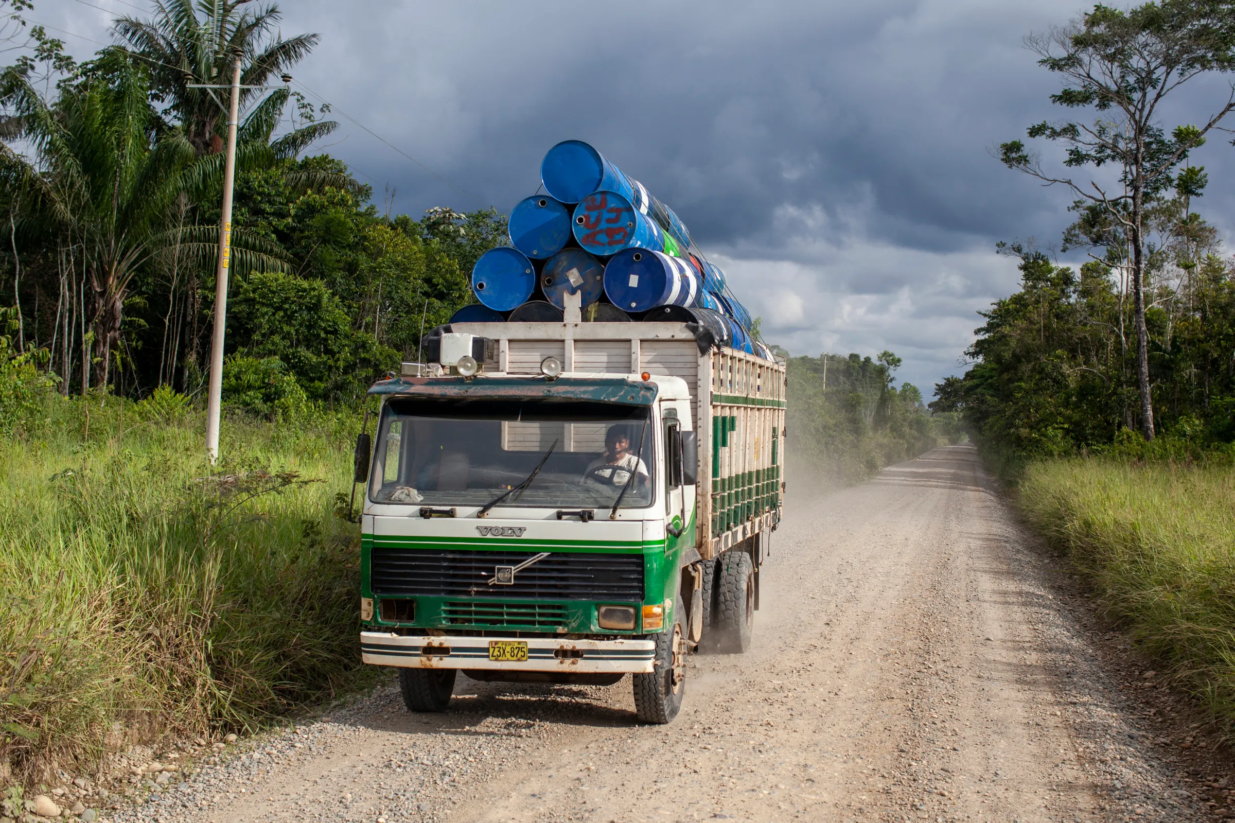 A truck transports barrels used in gold mining along the road to Delta 1, a mining settlement in the Amazon rainforest of Madre de Dios, Peru. The barrels are commonly repurposed as flotation devices. Madre de Dios, Peru. March 9, 2022. Alejandro Saldívar/Thomson Reuters Foundation