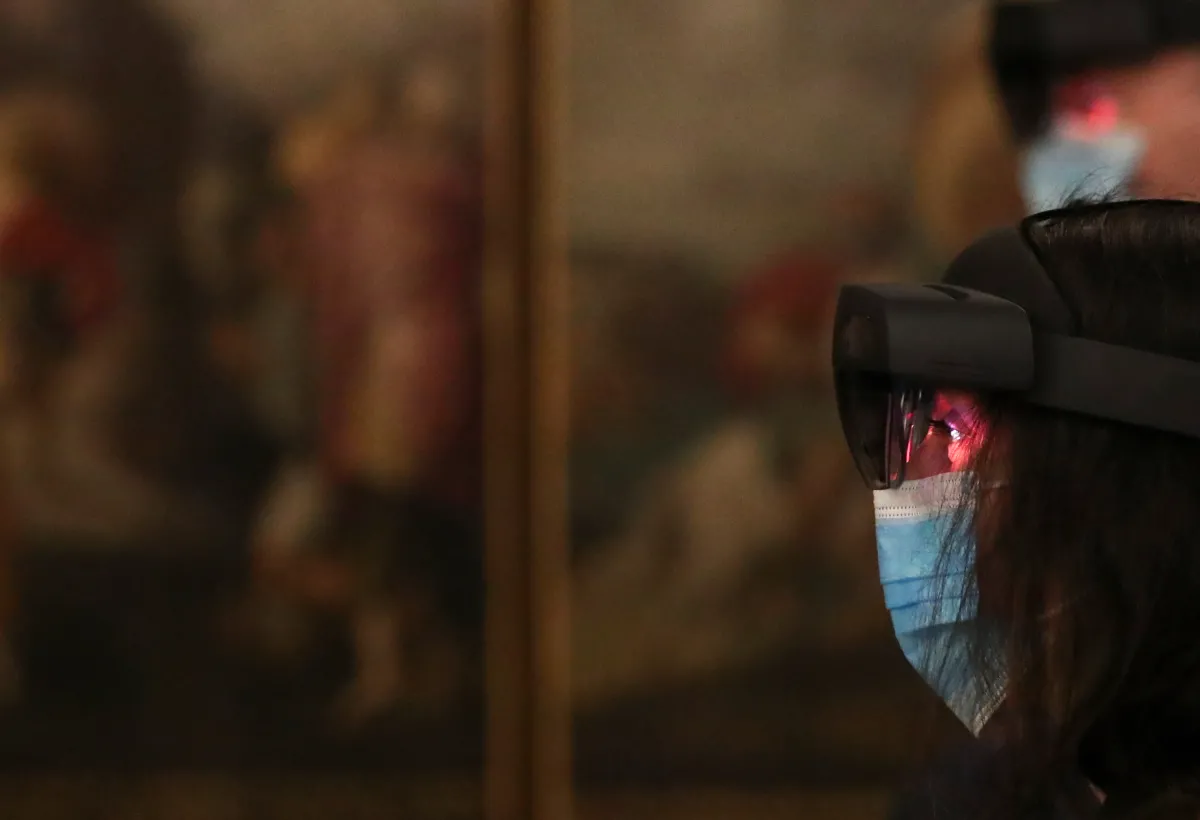 A visitor wears virtual glasses during a visit at St Bavo's Cathedral where Flemish painter Jan Van Eyck's 15th century masterpiece "Ghent Altarpiece" is displayed in a new multi-million euro exhibition space, equipped AI technology to plunge visitors into the painting, in Ghen, Belgium March 26, 2021. REUTERS/Yves Herman