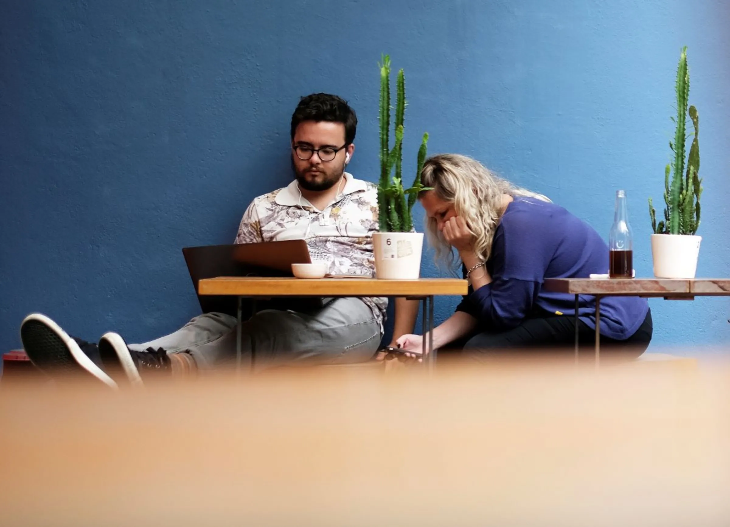 A man uses his computer next to a woman writing a message on her mobile phone at a cafe in Sao Paulo, Brazil October 17, 2017. REUTERS/Nacho Doce