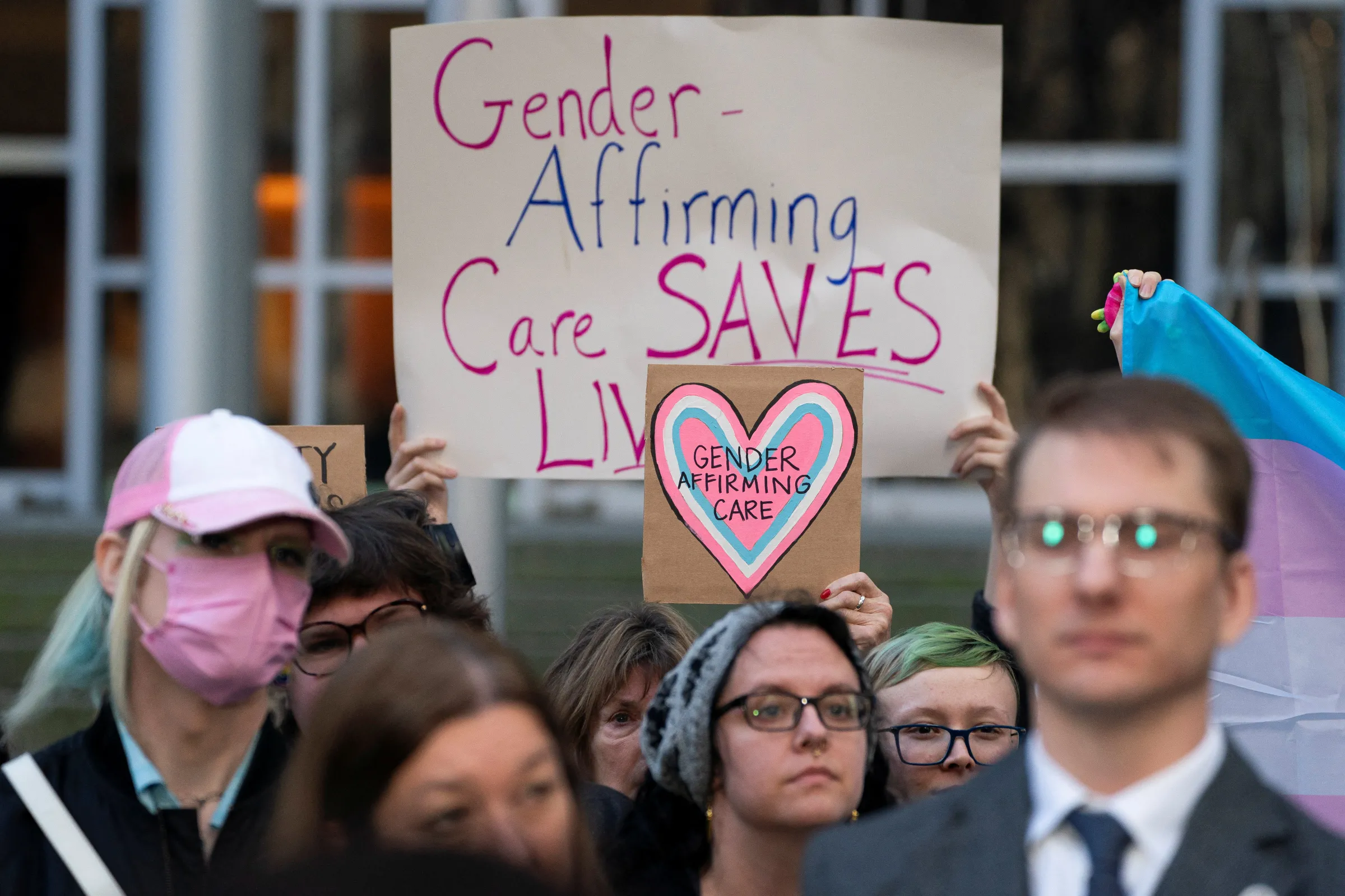 People hold pro-trans signs after a hearing in the multi-state lawsuit over President Trump's order ending all federal funding or support for healthcare that aids gender transitions for people younger than 19, outside a courthouse in Seattle, Washington, U.S., February 28, 2025. REUTERS/David Ryder