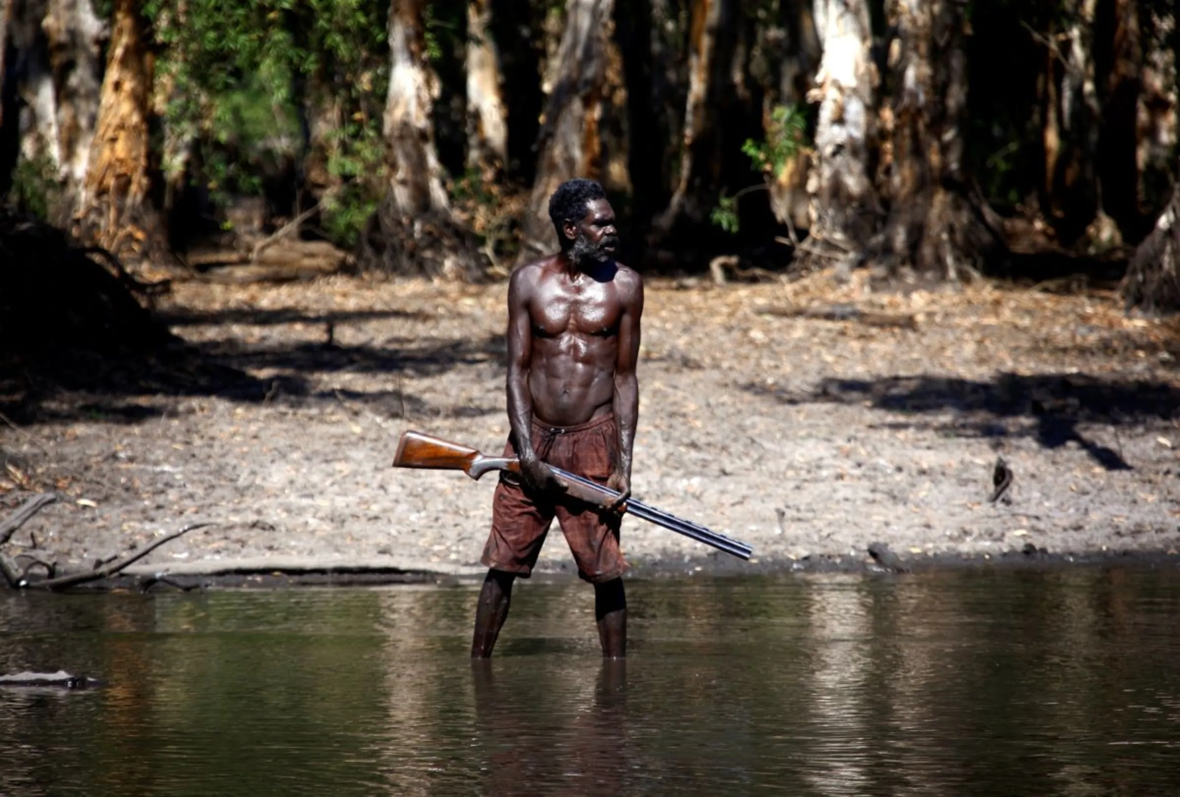 An Australian Aboriginal hunter of the Yolngu people stands in a billabong after shooting a crocodile near the 'out station' of Yathalamarra, in East Arnhem Land November 22, 2014. REUTERS/David Gray