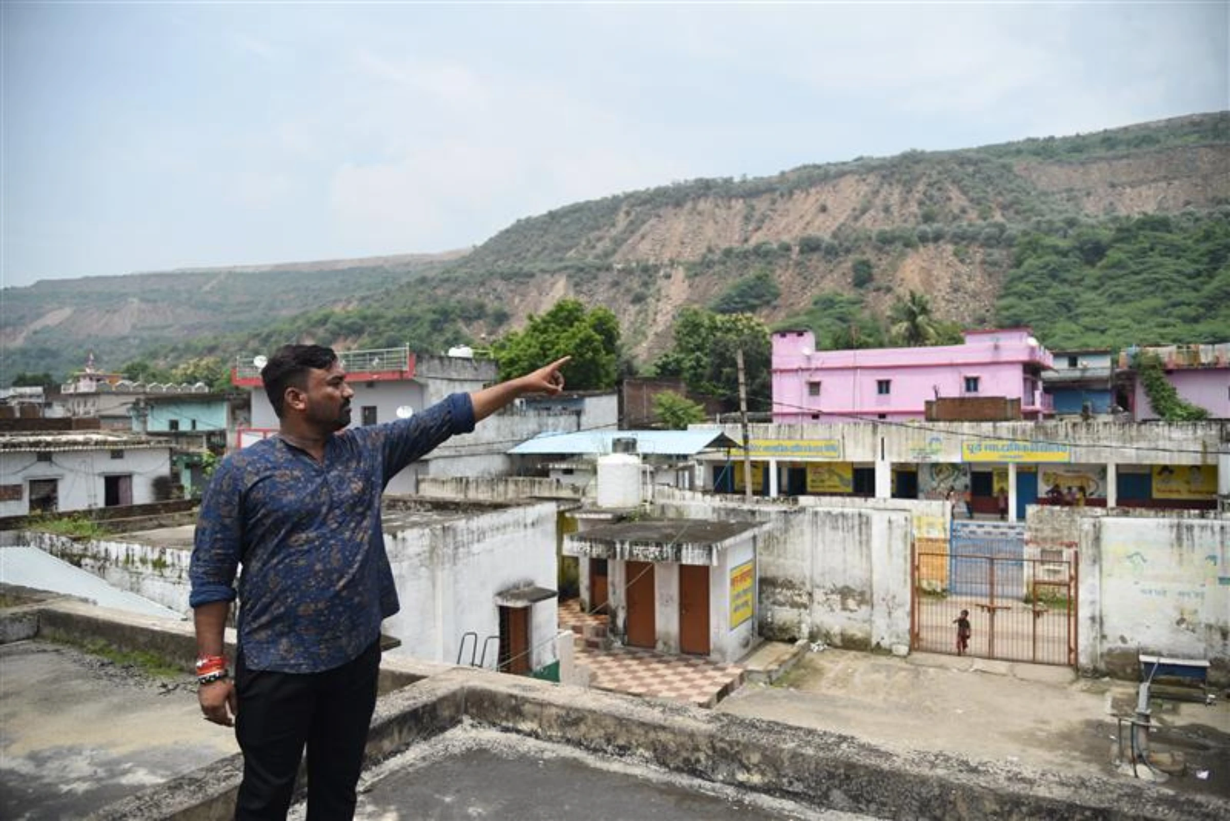 Manonit Ravi points out the mountain of mining debris few meters away from his village in Singrauli, India, on August 29, 2024. Thomson Reuters Foundation/Tanmoy Bhaduri