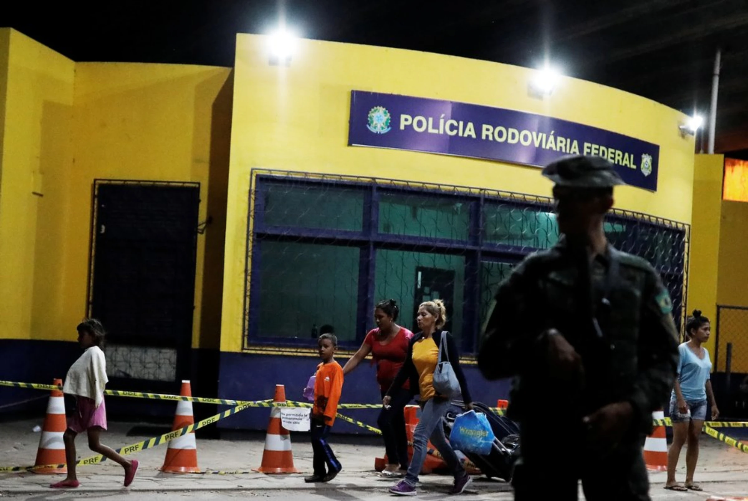 A military officer patrols as Venezuelan people walk towards Santa Elena to sleep, after showing their passports or identity cards at the Pacaraima border control, Roraima state, Brazil August 19, 2018