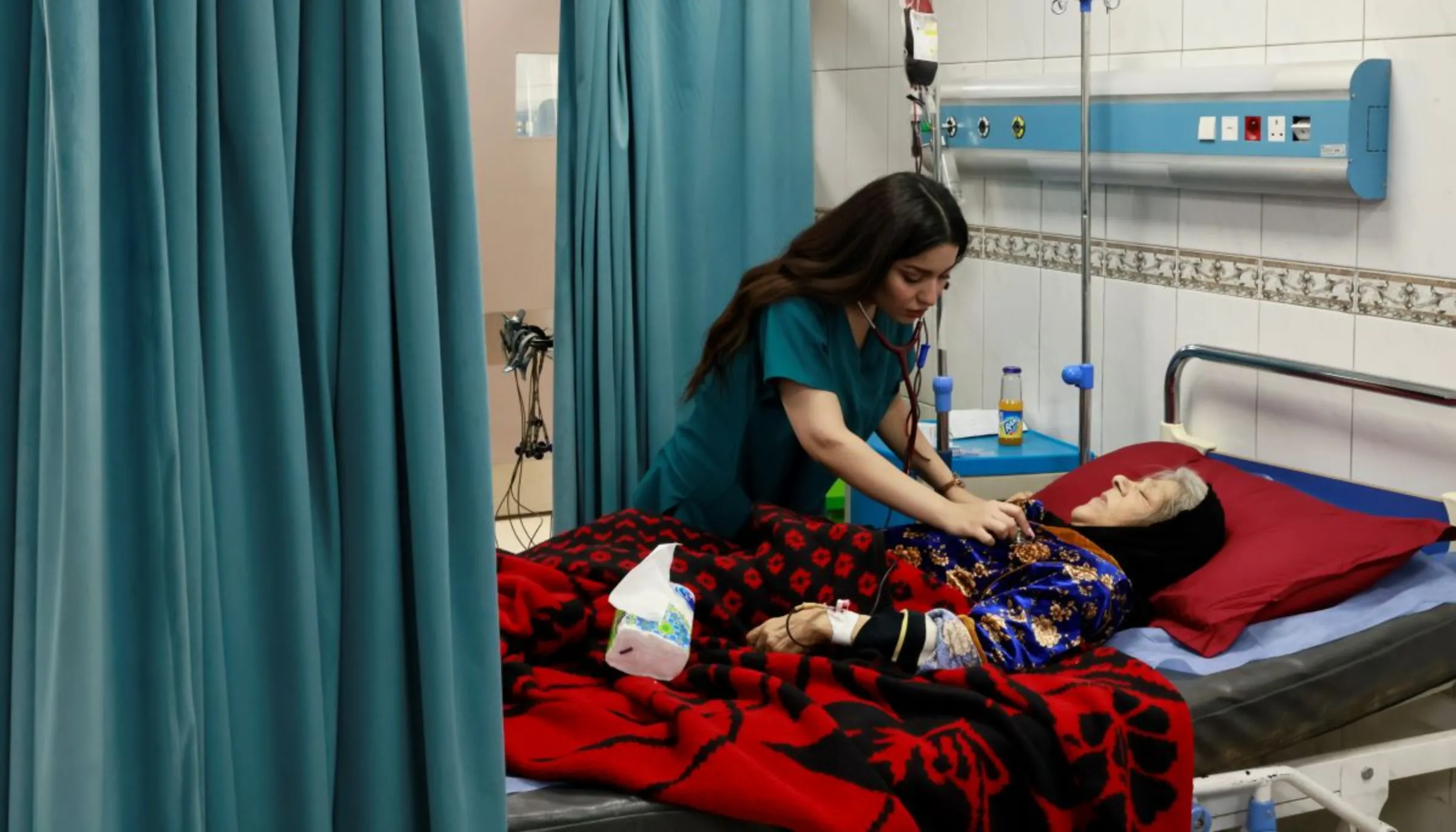 Dr. Amina Sabbar, 26, checks on an elderly woman. Baghdad, Iraq, March 6, 2023. Thomson Reuters Foundation/Abdullah Dhiaa al-Deen.