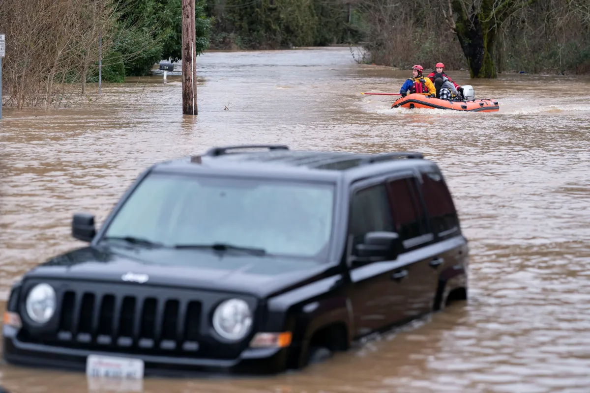 Water fills a car as Chehalis fire and rescue team members bring a stranded resident to dry land after floodwaters threatened their home following heavy rain in Chehalis, Washington, U.S., January 7, 2022. REUTERS/Nathan Howard
