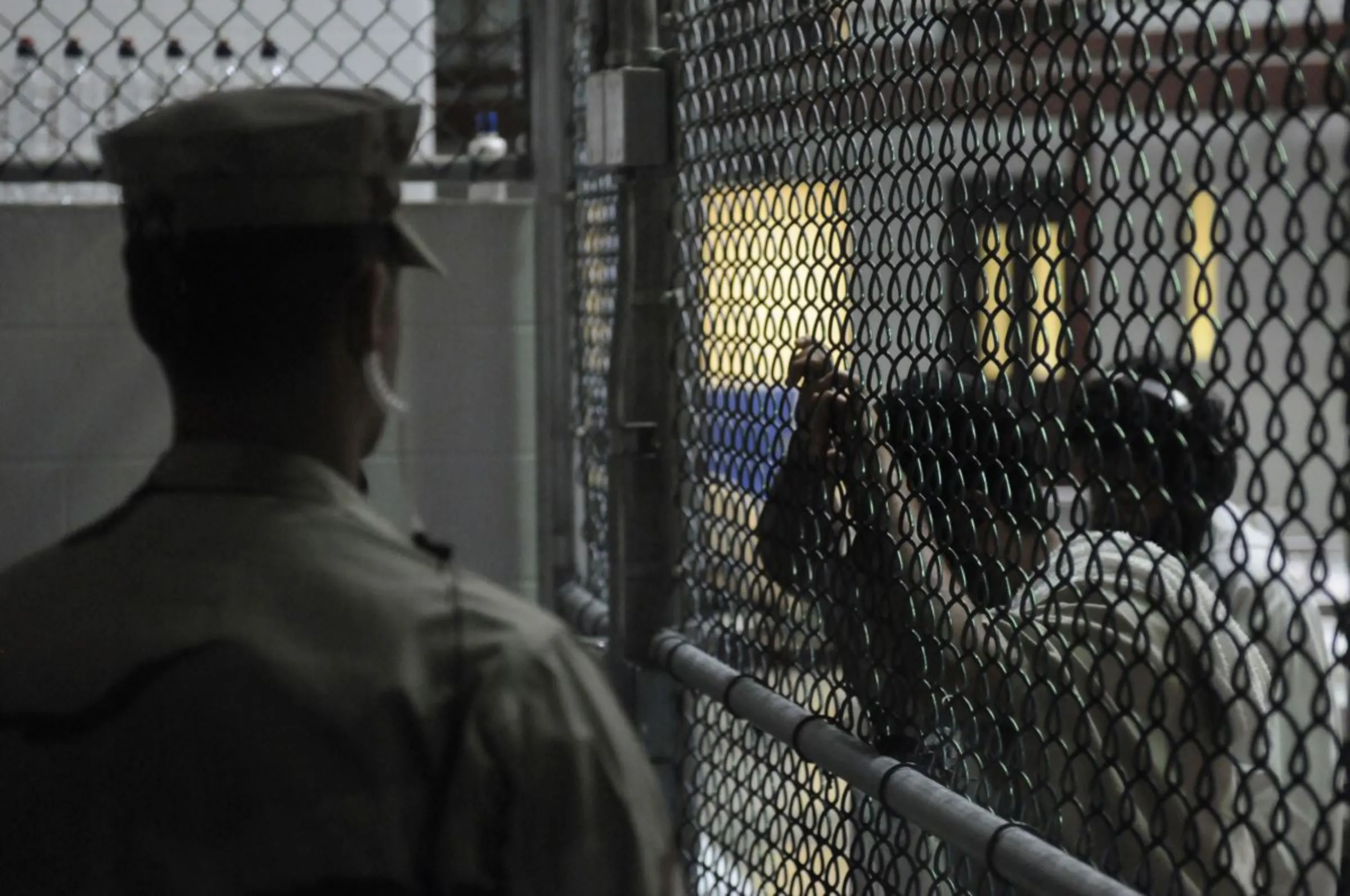 A Sailor assigned to the Navy Expeditionary Guard Battalion stands watch over detainees in a cell block in Camp 6 at Guantanamo Bay naval base in a March 30, 2010. REUTERS/MC3 Joshua Nistas/US Navy/Handout via Reuters