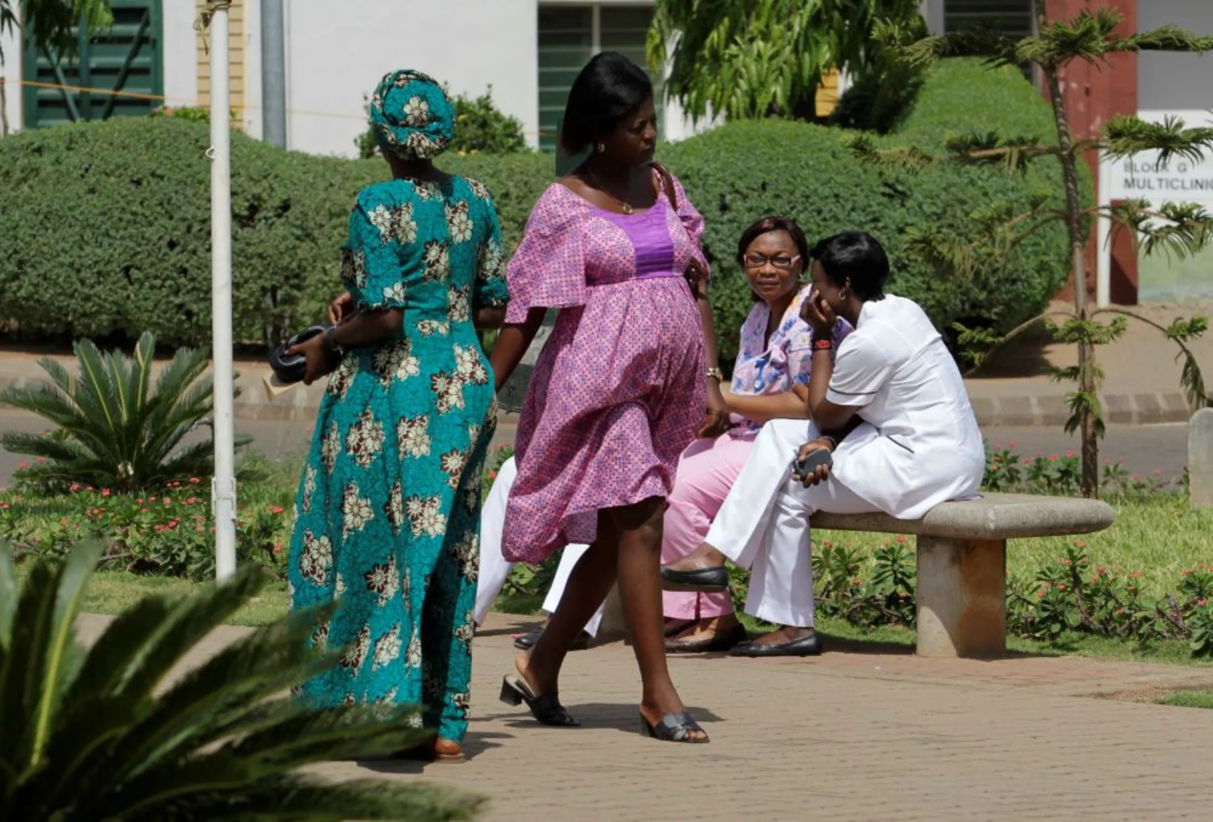 A pregnant woman walks past healthcare workers of National Hospital Abuja, outside the hospital in Abuja, Nigeria March 5, 2013
