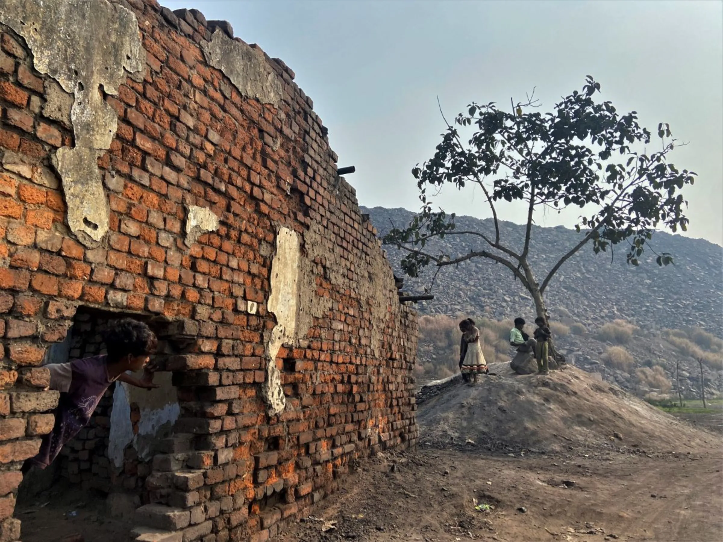 Children play in front of a hillock of debris from recent mine excavations at Golakdhi settlement in Jharia coalfield, India, on November 10, 2022. Thomson Reuters Foundation/Roli Srivastava