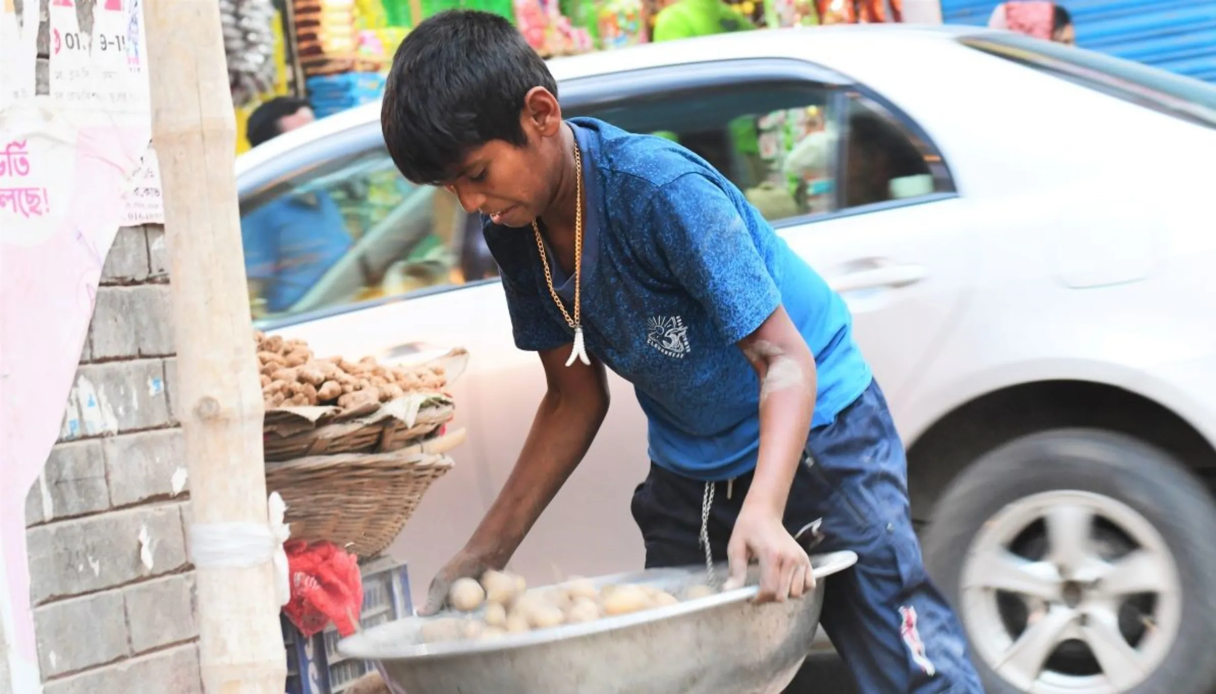 Alauddin, 10, whose family lost their home to flooding last year, works at a vegetable stand in Dhaka, Bangladesh, March 18, 2022. Thomson Reuters Foundation/Mosabber Hossain