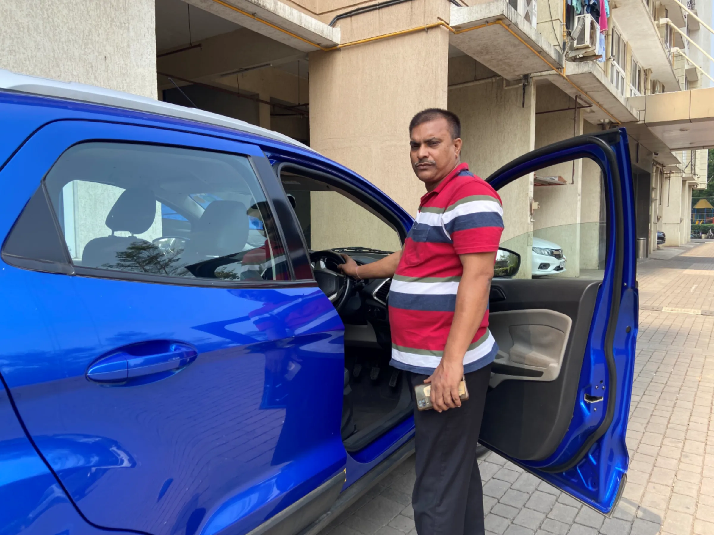 Chauffeur Nutan Pathak poses for a picture in front of his employer’s car in Mumbai, India, where he migrated from his family farm across the country to find work, Oct 31, 2023. Thomson Reuters Foundation/Roli Srivastava