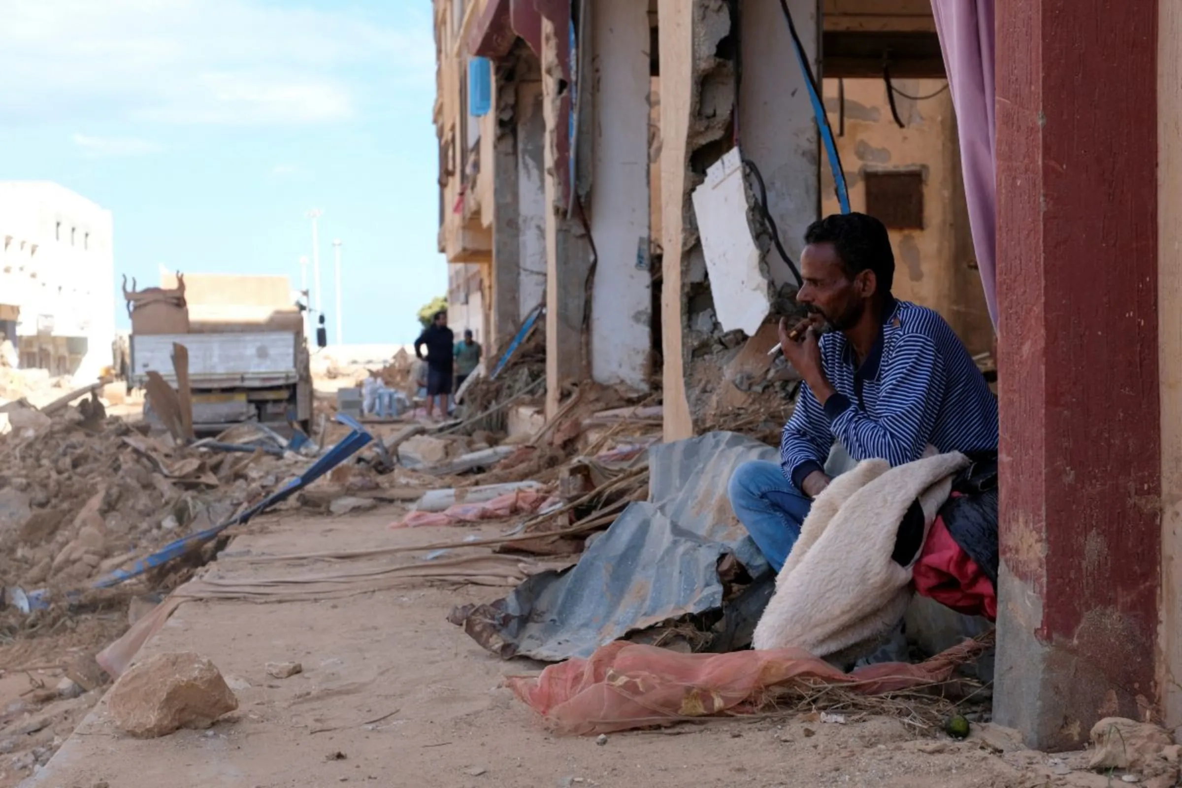 A man sits next to damaged buildings impacted by fatal floods in Derna, Libya, September 28, 2023. REUTERS/Esam Omran Al-Fetori