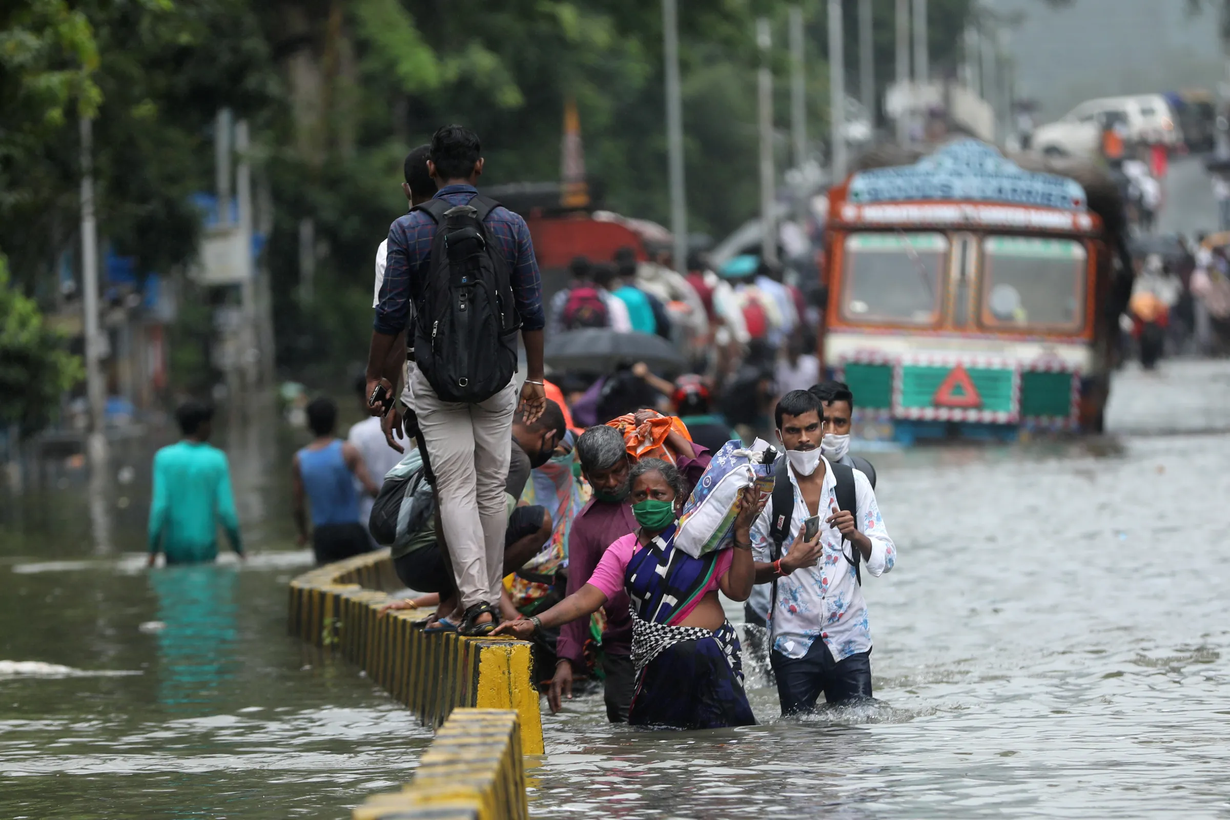 People wade through a waterlogged road after heavy rainfall in Mumbai