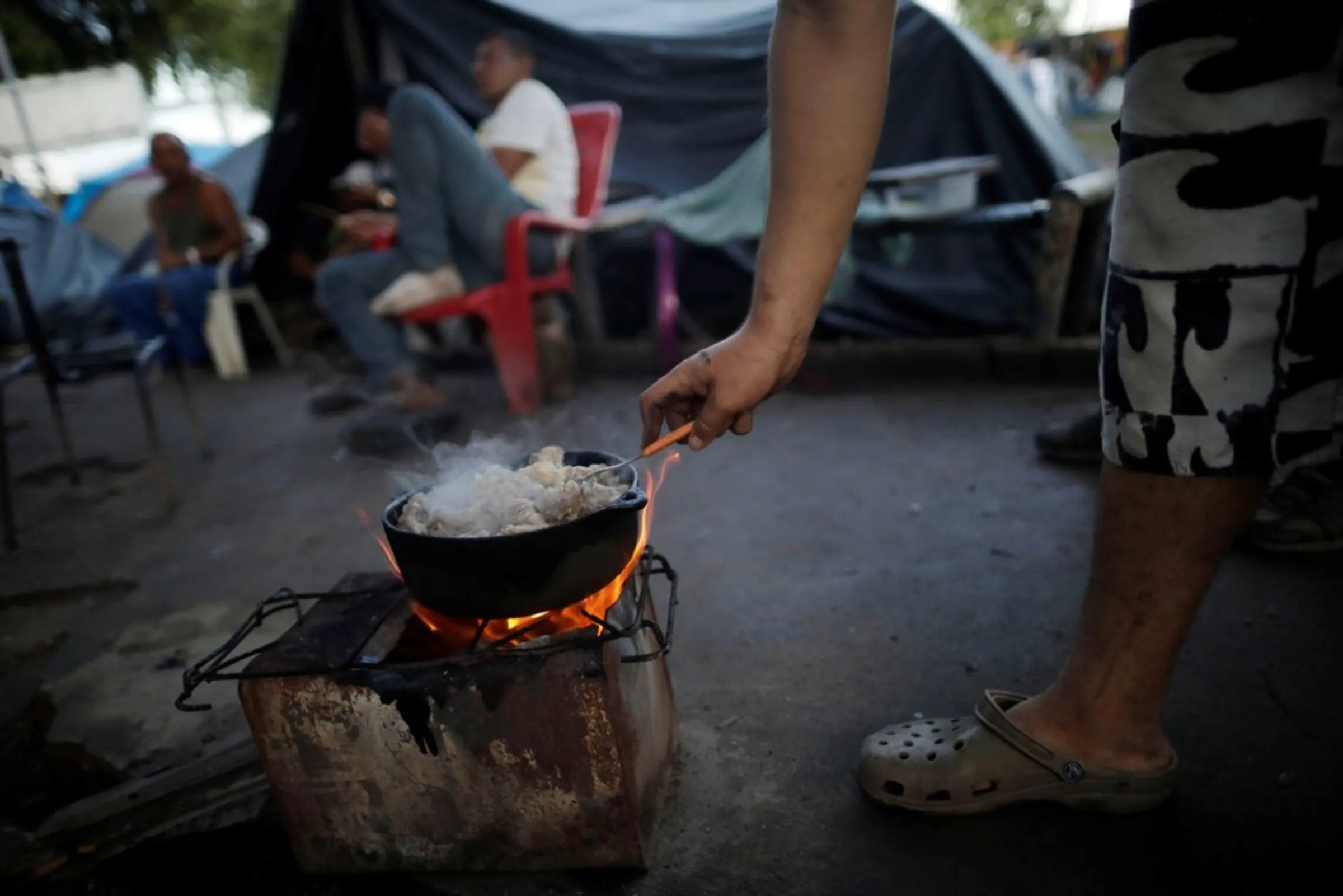 A Venezuelan migrant stands by a stove at a makeshift camp at Simon Bolivar square in Boa Vista, Brazil May 3, 2018