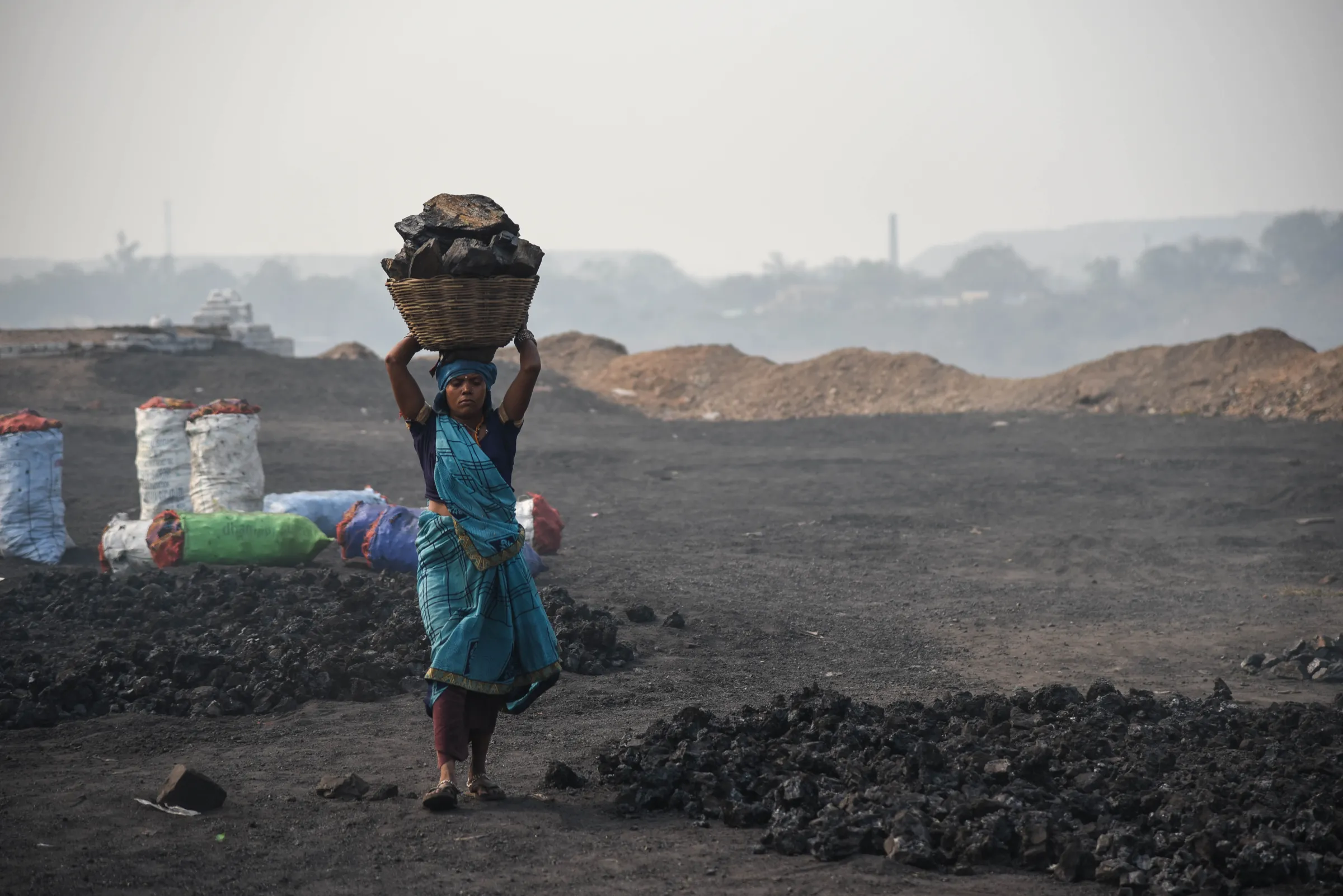 A woman carries a basket of coal she picked on the fringes of a coalfield in Jharia, India, November 11, 2022. Thomson Reuters Foundation/Tanmoy Bhaduri 