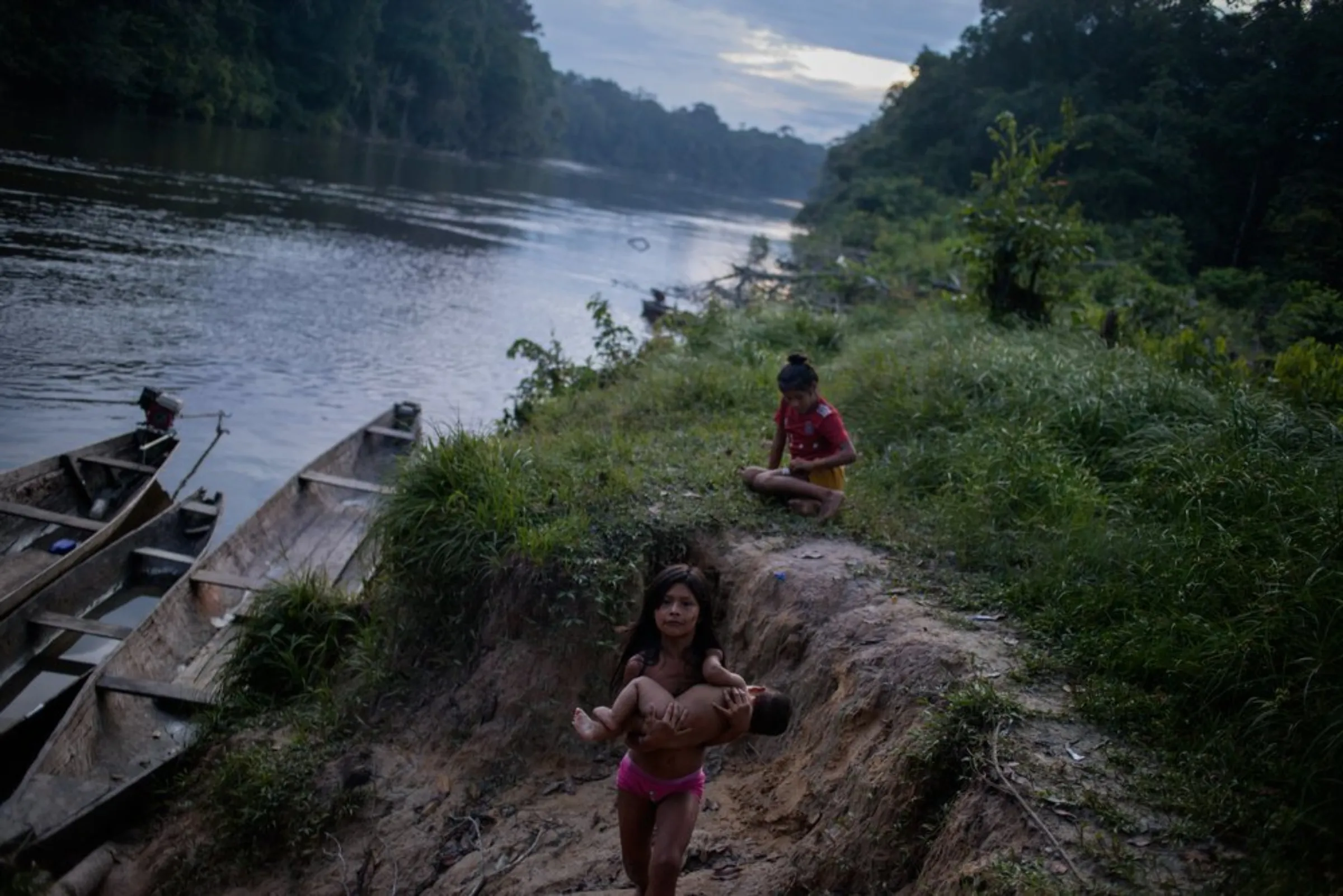 Indigenous children work and play along the bank of the Miriti-Parana River at the Puerto Libre community in Colombia’s southeast Amazonas province. Dugout canoes are the main form of transport in a region with no roads. December 19, 2021