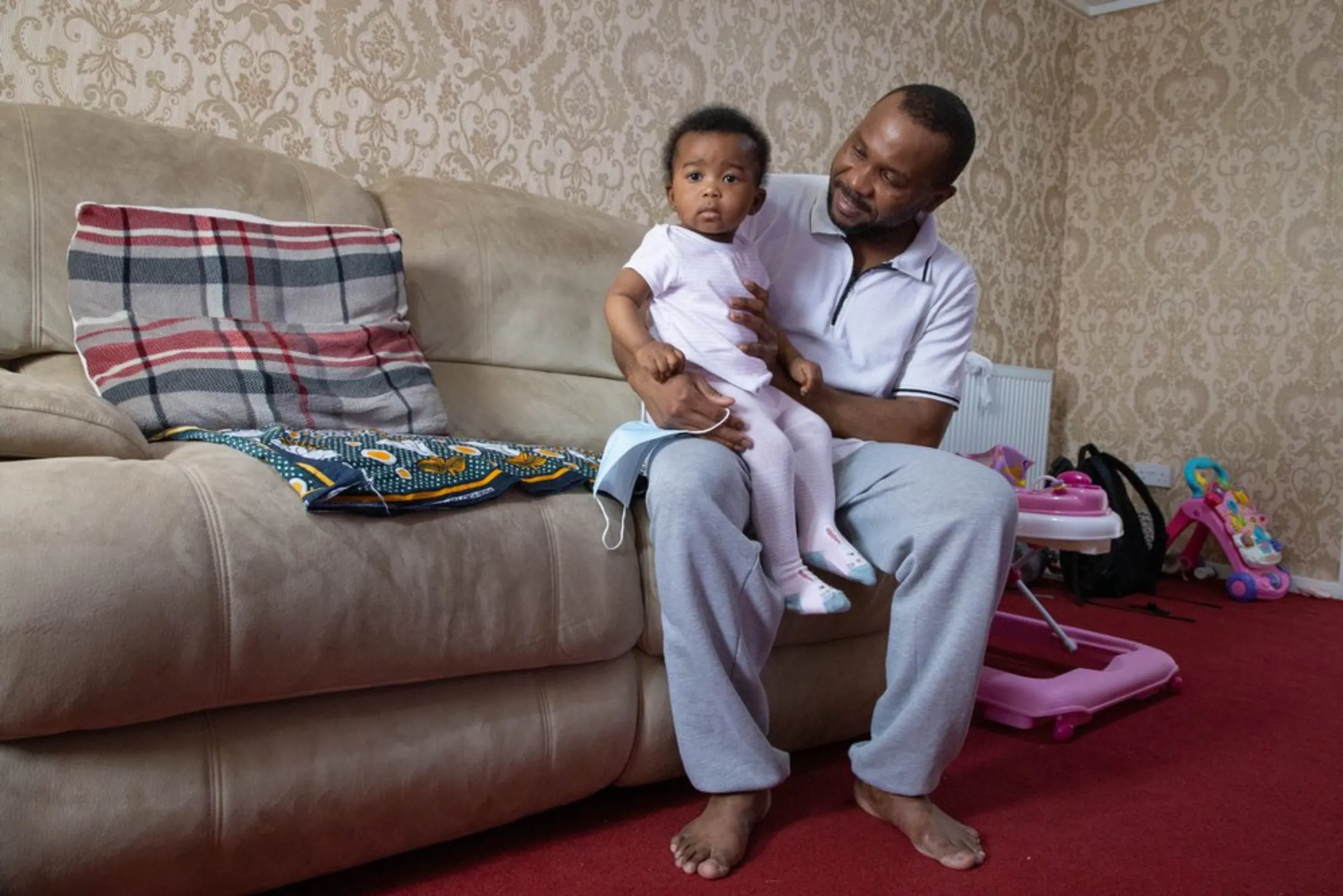 Tizo Seleman holds his baby daughter in his home in Glasgow, United Kingdom, July 22, 2021. Seleman and his partner expect their bills to shrink now that their social housing landlord has replaced old heaters with an air-source heat pump