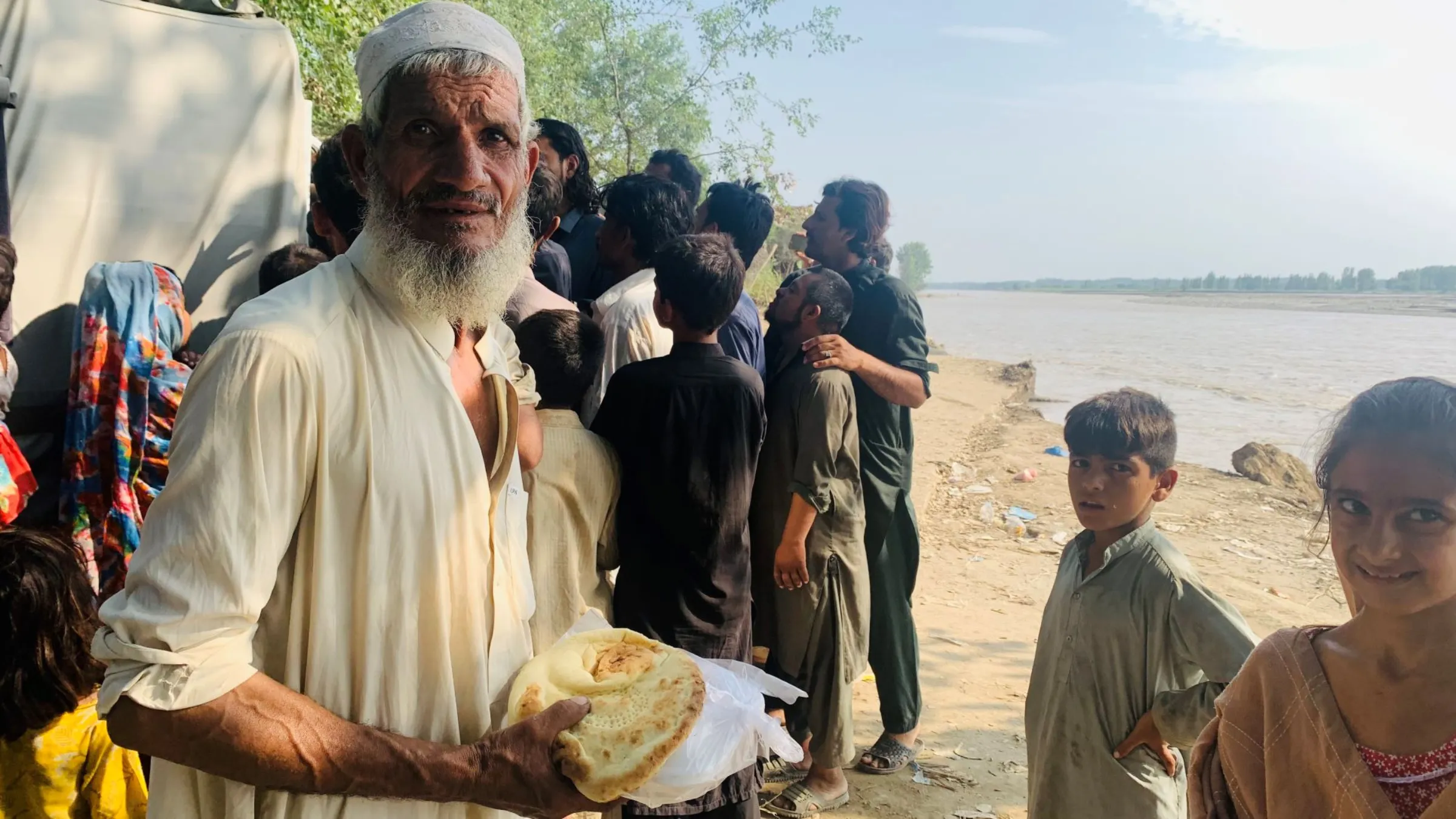 A flood-affected older man gets free food provided by a local philanthropist on the banks of the Swat River in Dagi Mukarram Khan, a village in Charsadda district in Pakistan’s northwest Khyber Pakhtunkhwa province, September 1, 2022. Thomson Reuters Foundations/Imran Mukhtar