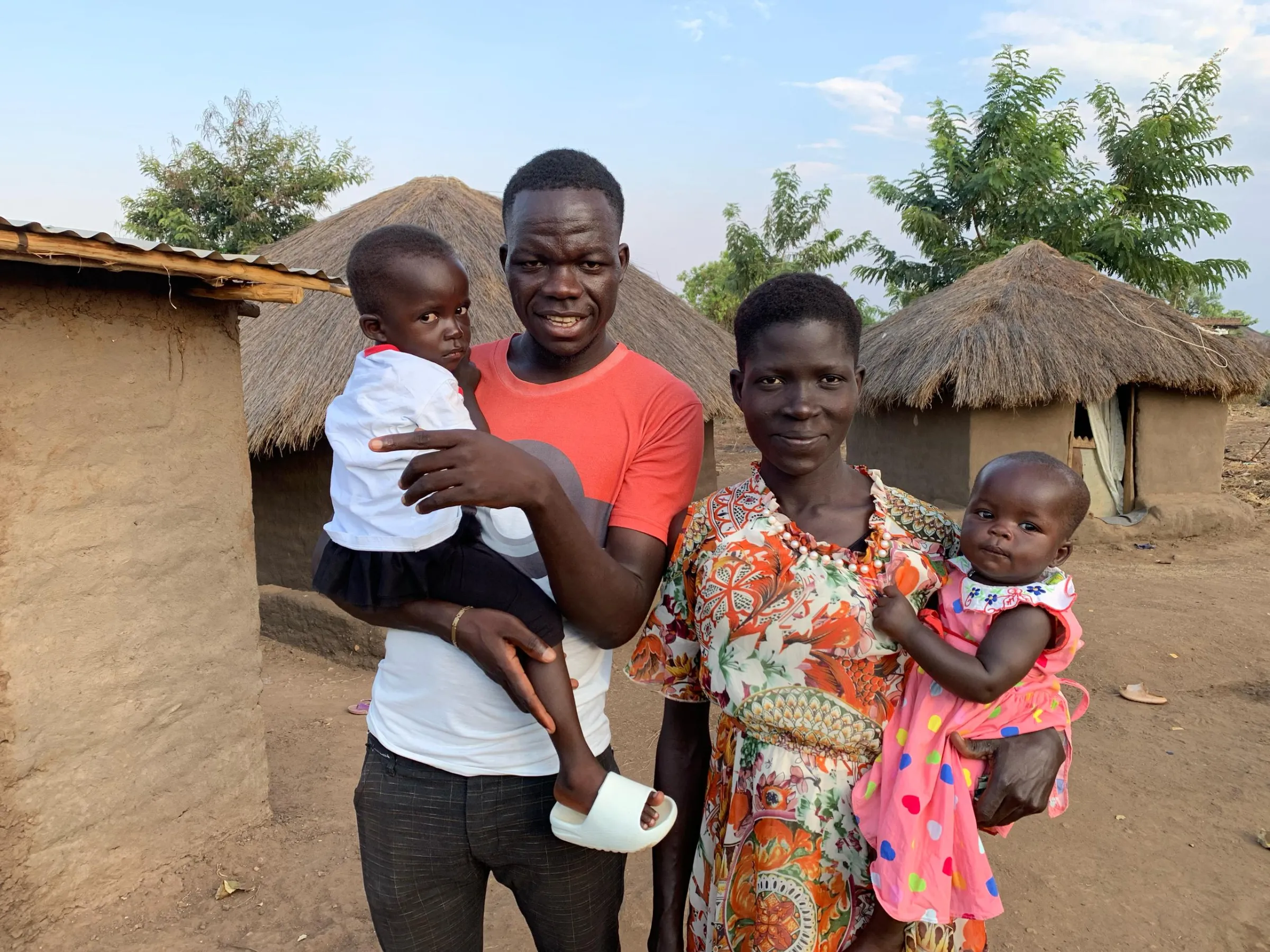 Yesua Aliki stands outside his home in Bidibidi with his wife Besta Ajio, daughter Grace Senema, 3, and baby Patience Onjiro. February 2025. Yesua Aliki/Handout via Thomson Reuters Foundation