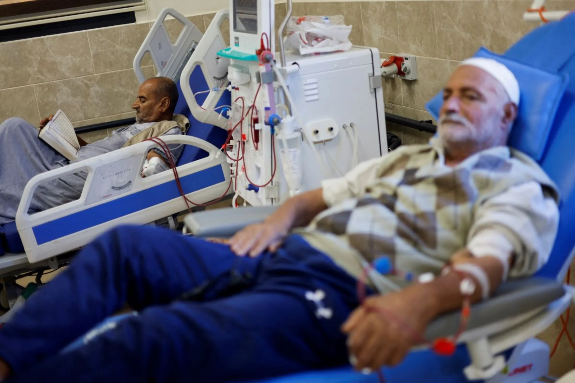 A Palestinian kidney patient reads while lying on a hospital bed, as health officials say they are running out of fuel to operate dialysis devices, amid the ongoing Israeli-Palestinian conflict, at Naser hospital in Khan Younis in the southern Gaza Strip October 15, 2023. REUTERS/Mohammed Salem