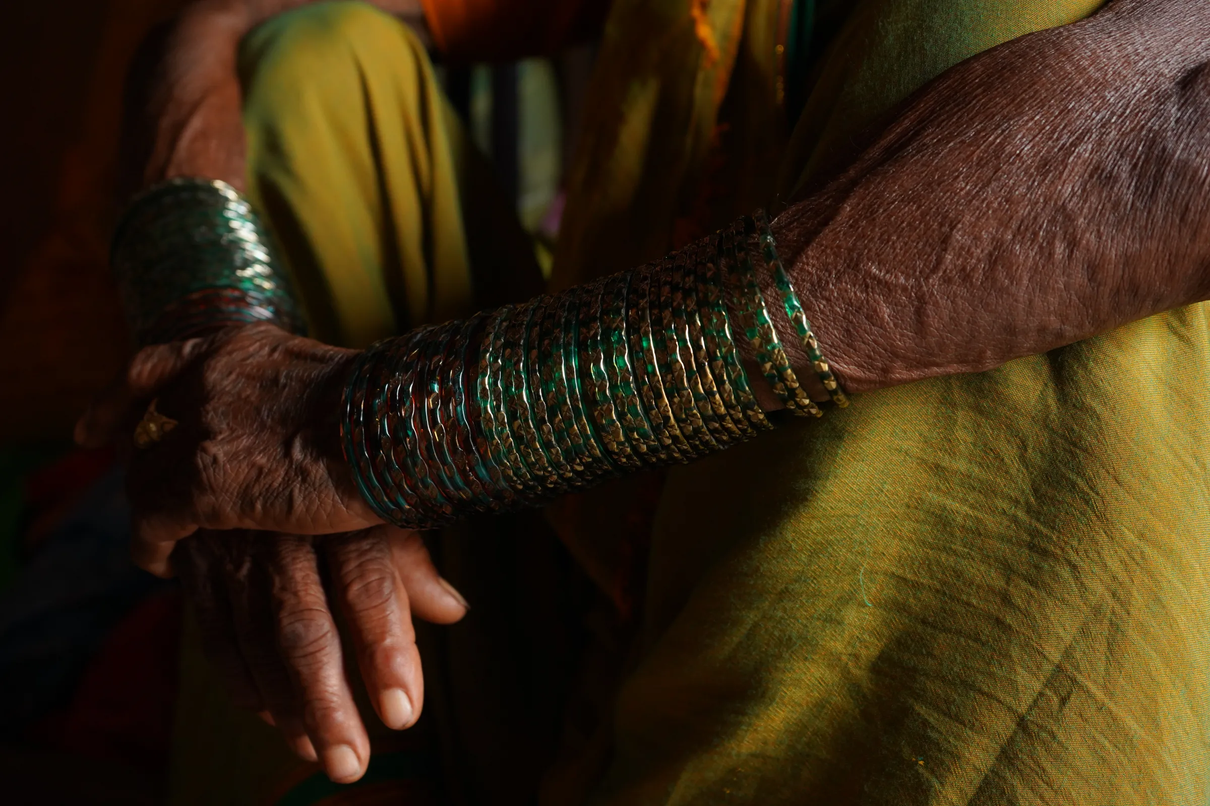 Farmer Hirabai Shankar Kalel sits on the floor, wrapping her hands covered with glass bangles around her legs, at Jambhulni village in Satara district, India, September 14, 2022
