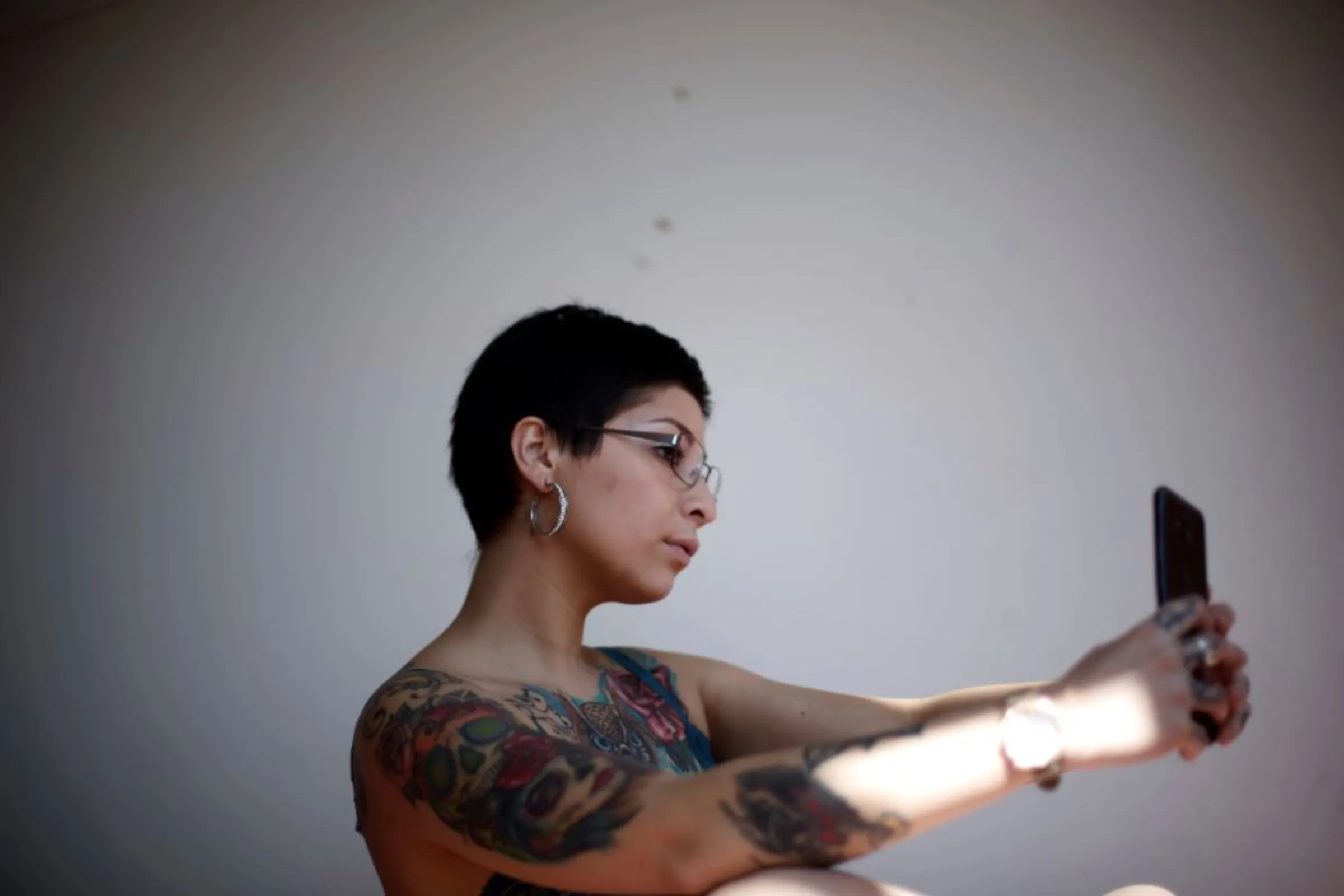 An online sex worker uses a mobile phone as she prepares herself to start a meeting with a customer online, in Concepcion, Chile April 7, 2020.REUTERS/Juan Gonzalez