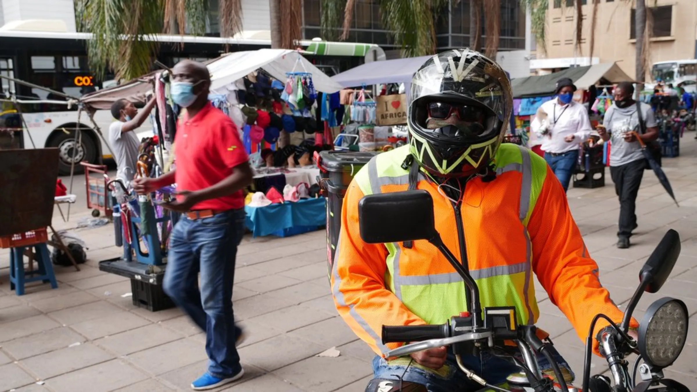 Burundian food courier, John, poses for a photo in front of a street market in Pretoria, South Africa. February 9, 2020. He used to drive for grocery delivery service Checkers Sixty60. Thomson Reuters Foundation/Kim Harrisberg