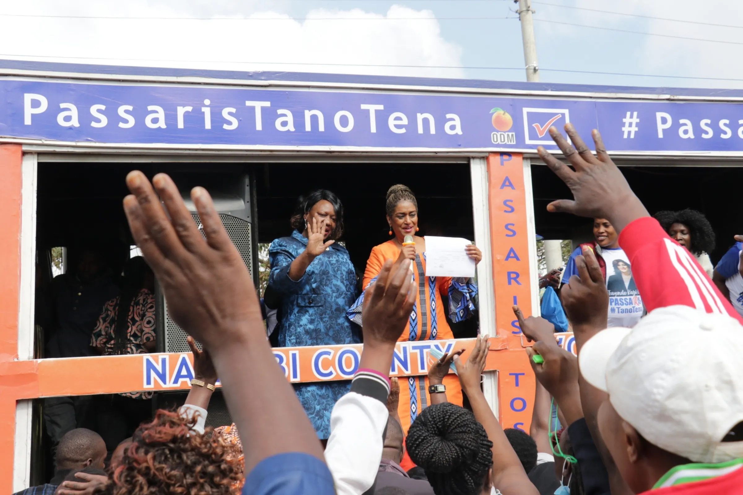 Female politicians wave from a campaign tent