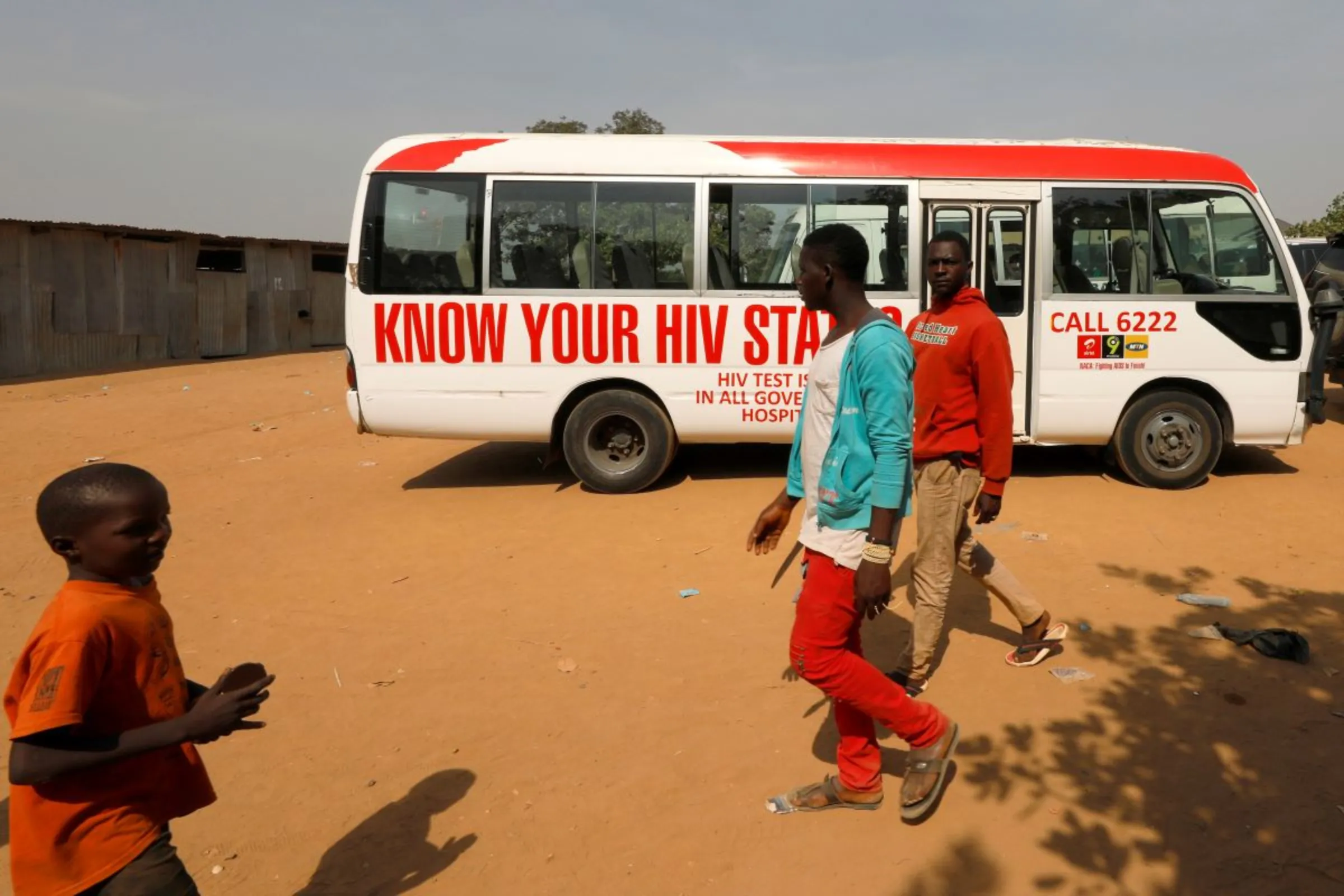 People walk past a bus during an HIV/AIDS awareness campaign on the occasion of World AIDS Day at the Kuchingoro IDPs camp in Abuja, Nigeria December 1, 2018. REUTERS/Afolabi Sotunde