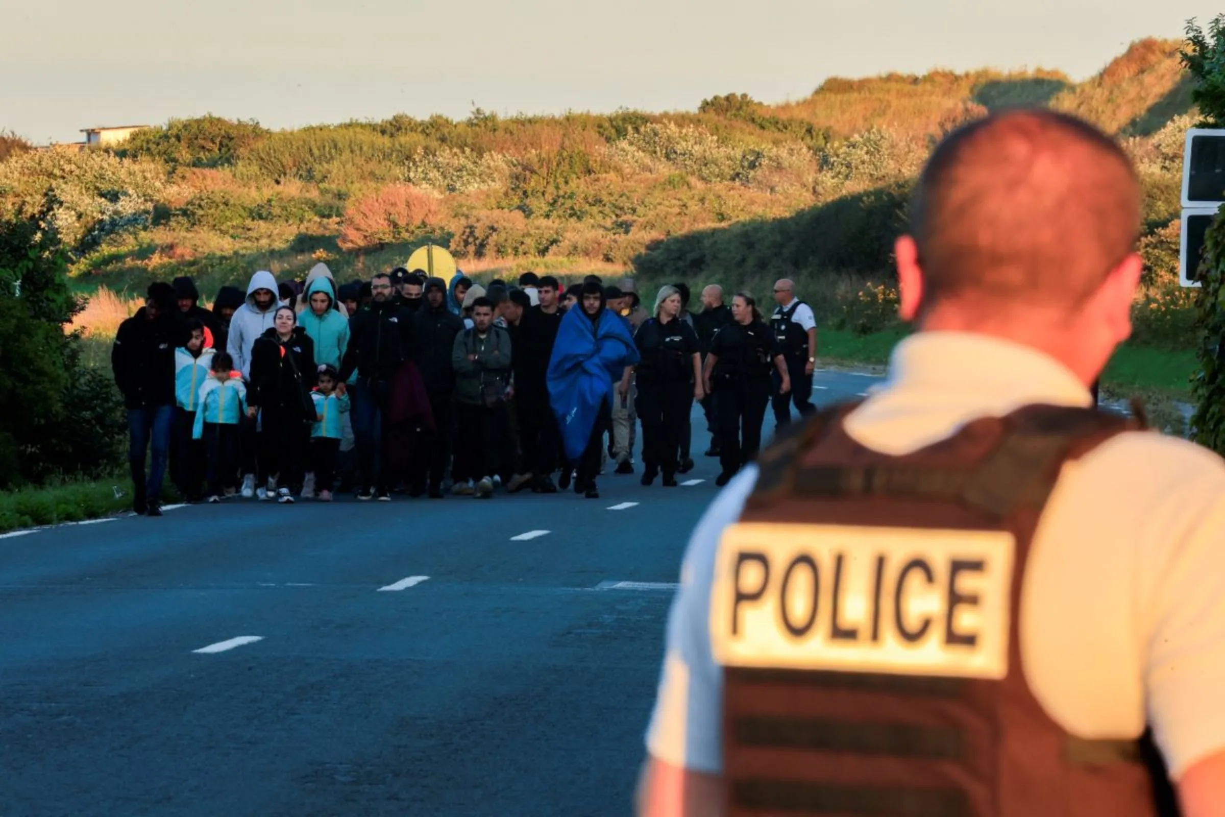 A group of migrants walk back to their makeshift camp at sunrise after a failed attempt to cross the Channel to the UK on a small boat, in Sangatte, near Calais, France, August 10, 2023