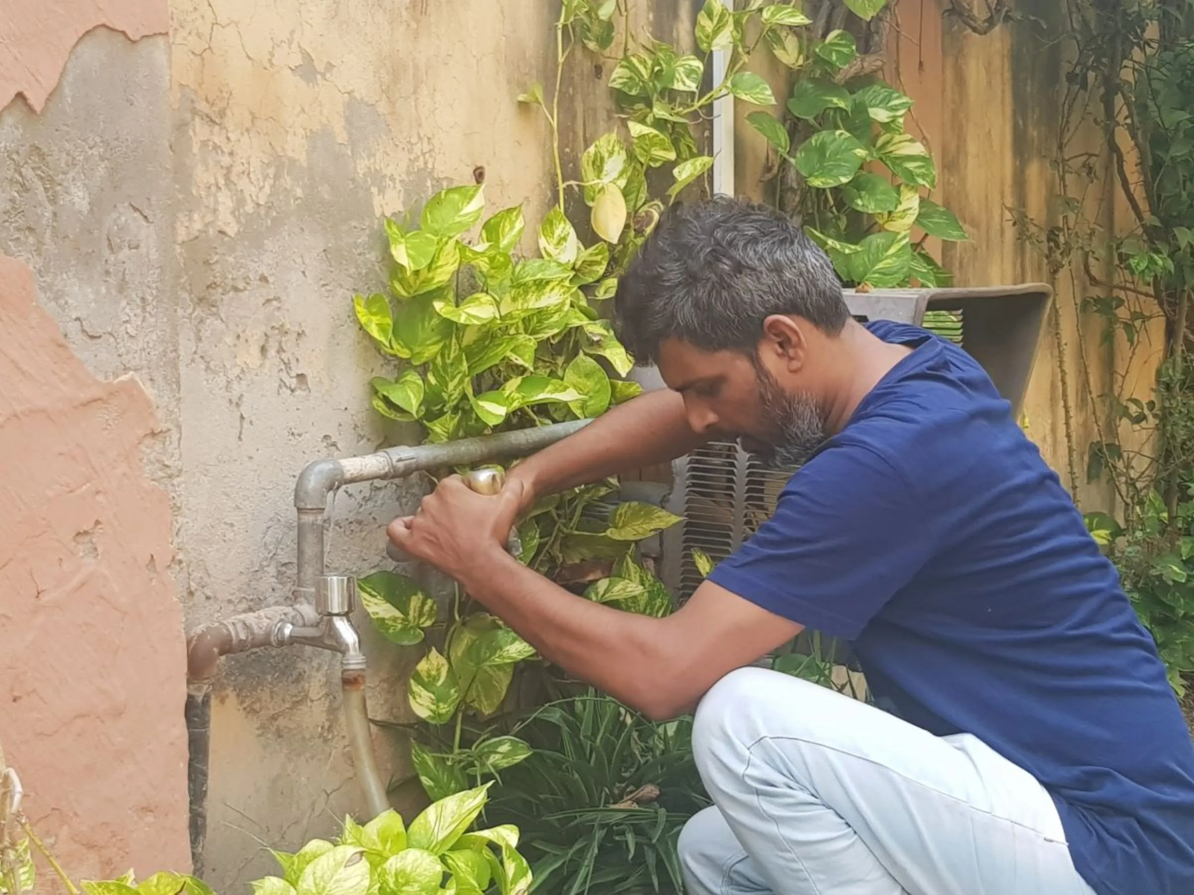 Muhammad Aslam, a plumber, fixes a leaking tap at a house in Lahore, Pakistan, September 27, 2023. Thomson Reuters Foundation/Waqar Mustafa