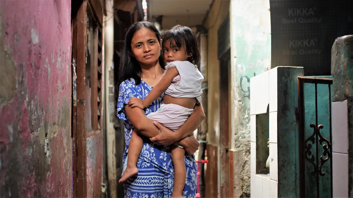 Kusdriyana, a housewife, holds her child in her home in Pisangan Baru in Jakarta, Indonesia.