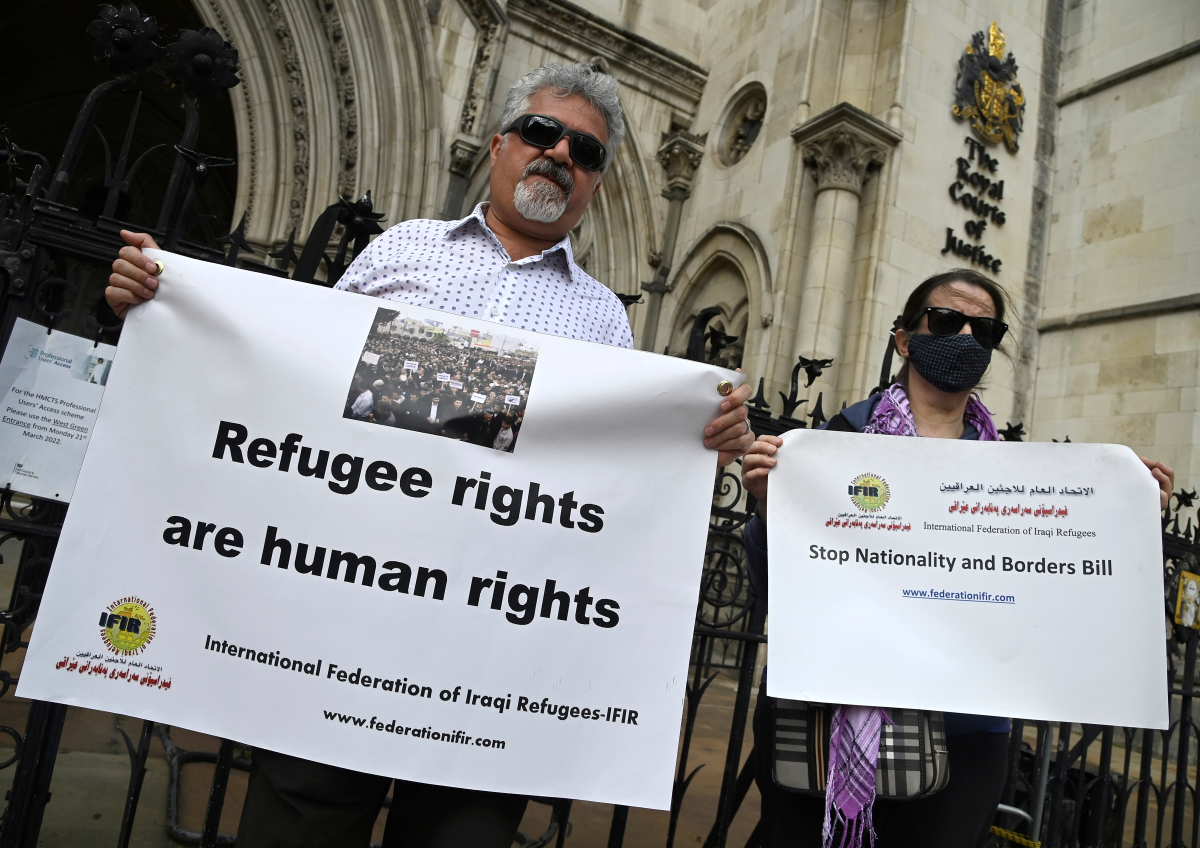 Demonstrators hold placards outside the royal courts of justice